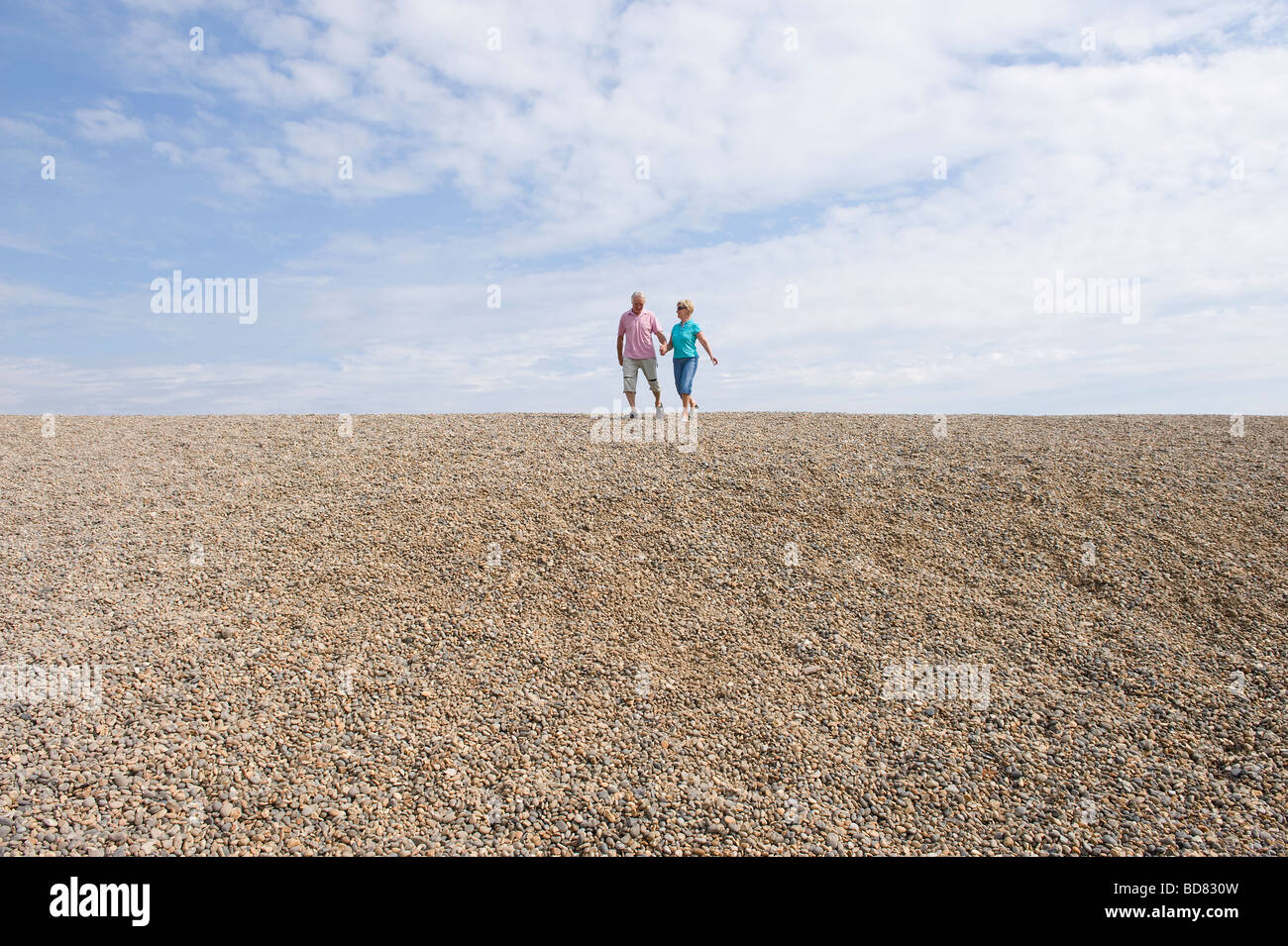 Älteres Paar zu Fuß am Kiesstrand Stockfoto