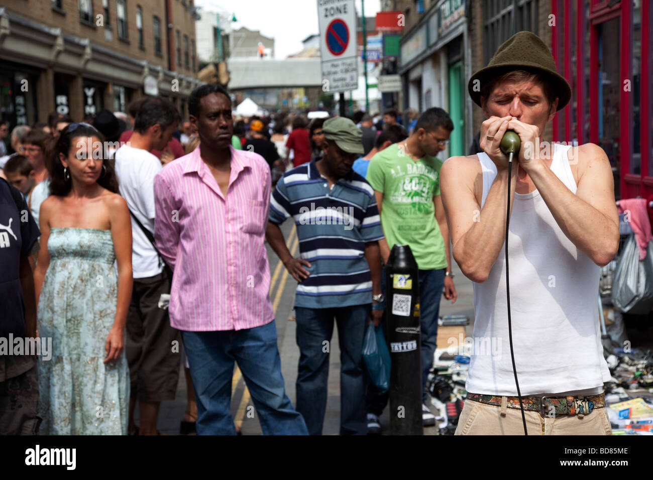 Mundharmonika-Spieler unterhält die Massen an Brick Lane Market. Dieser Markt ist ein wöchentliches Event am Sonntag in London s Ostende. Stockfoto