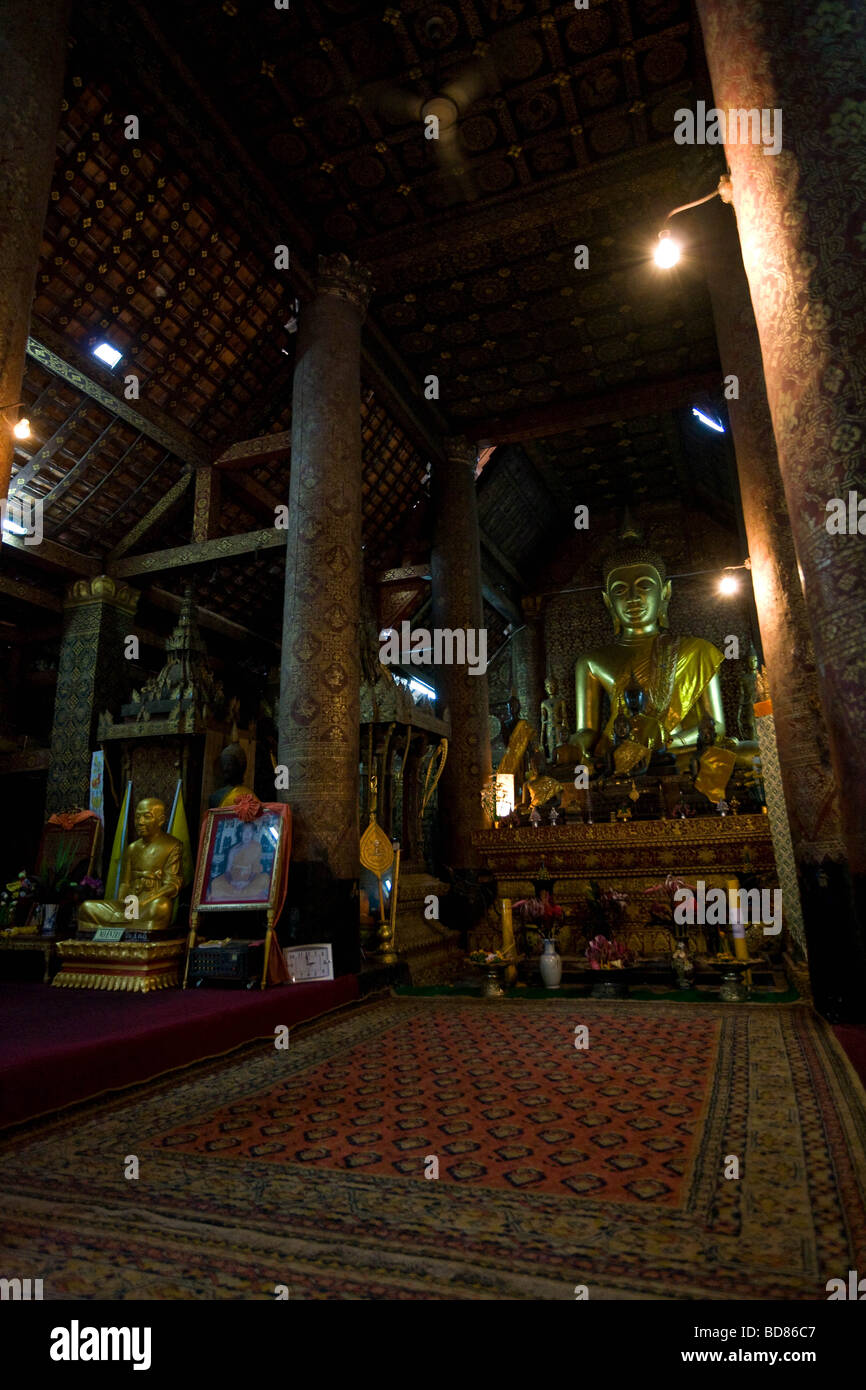 Innerhalb Wat Xieng Tong, Luang Prabang, sieht ein vergoldeter Buddha-Status über das reich ausgestattete Zimmer. Stockfoto