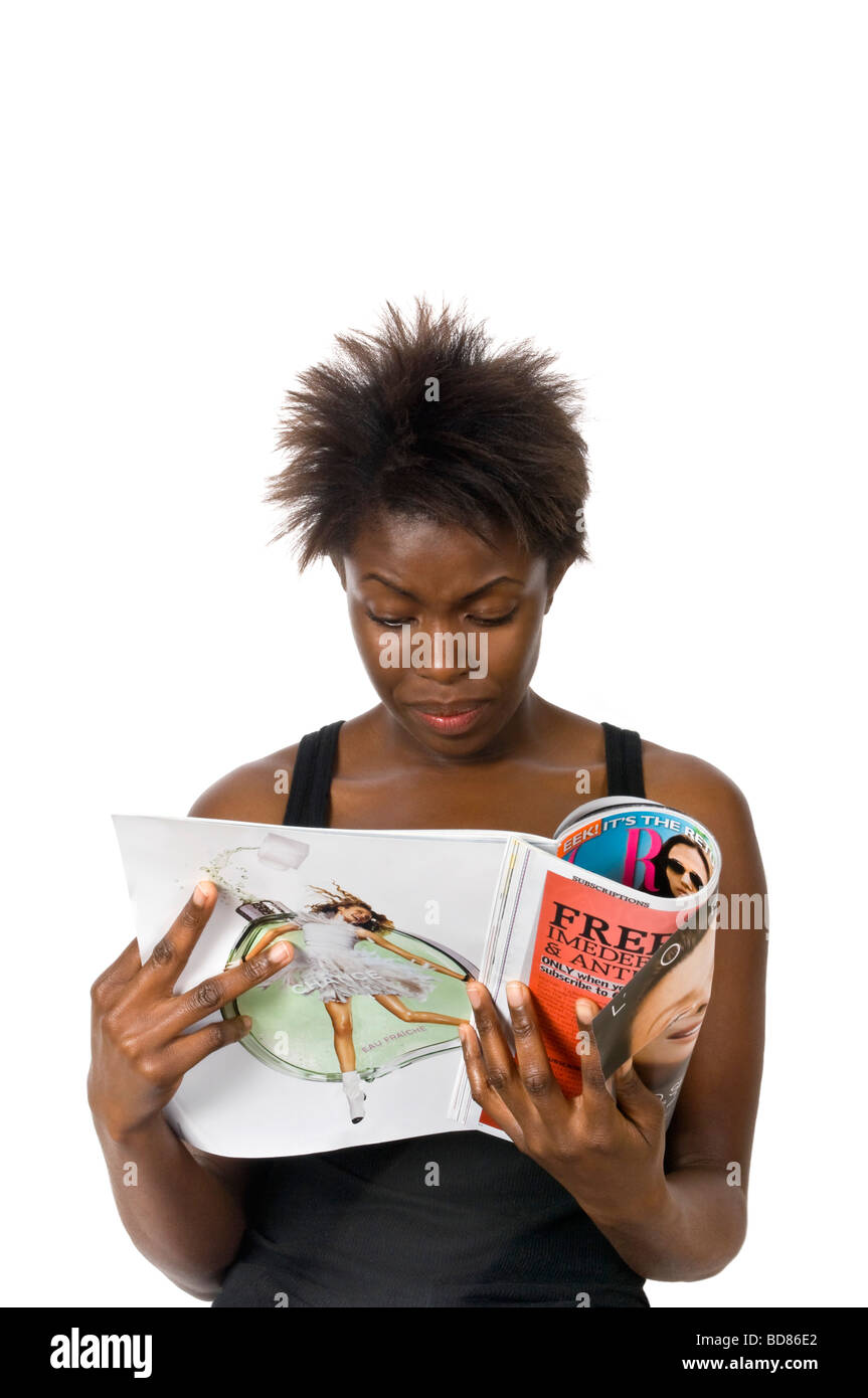 Vertikal nah Porträt eine attraktive Afrikanerin runzelt die Stirn eine Modezeitschrift vor einem weißen Hintergrund zu lesen Stockfoto