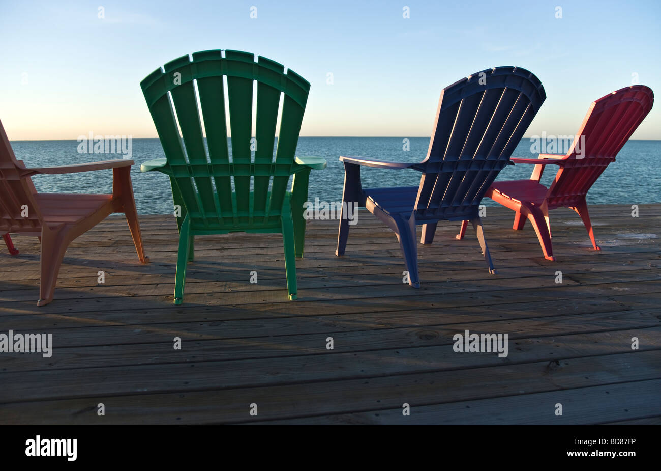 Bunte Stühle auf der Mole mit Blick auf Bucht. Stockfoto