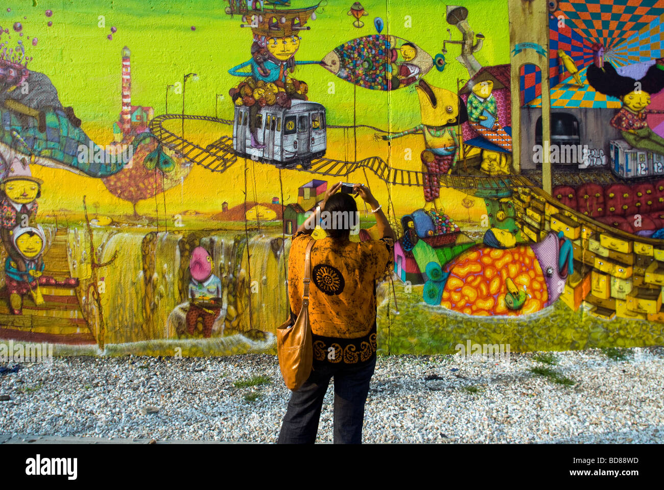 Passant fotografiert ein Wandbild von der brasilianischen Graffiti-Künstlern Os Gémeos in New York Stockfoto