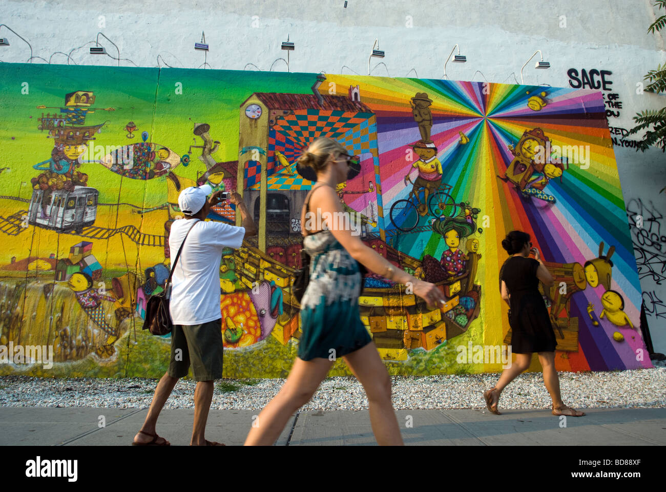 Passanten beobachten oder ein Wandbild von der brasilianischen Graffiti-Künstlern Os Gémeos in New York zu ignorieren Stockfoto
