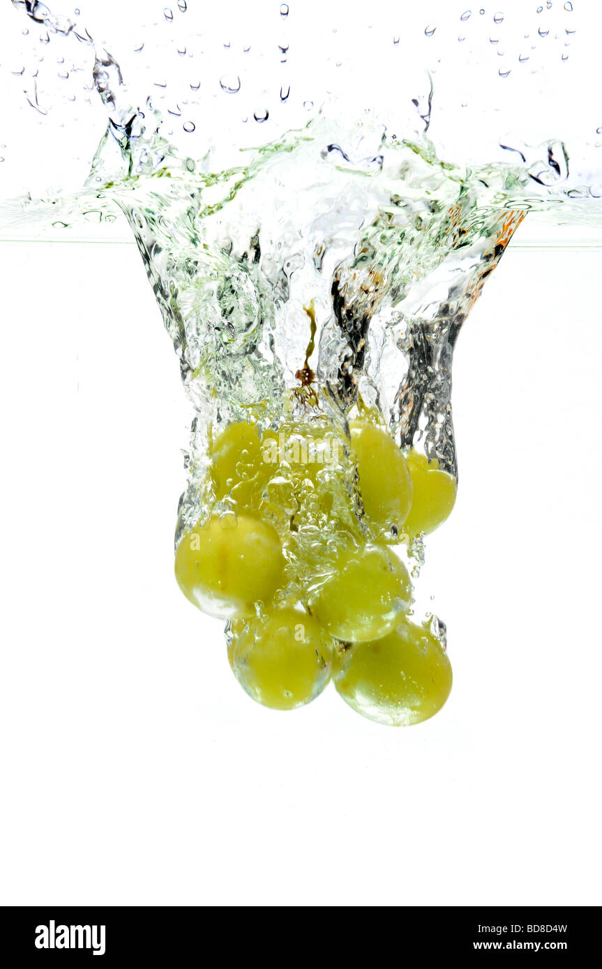 Grüne Trauben spritzt ins Wasser über einen weißen Hintergrund Stockfoto