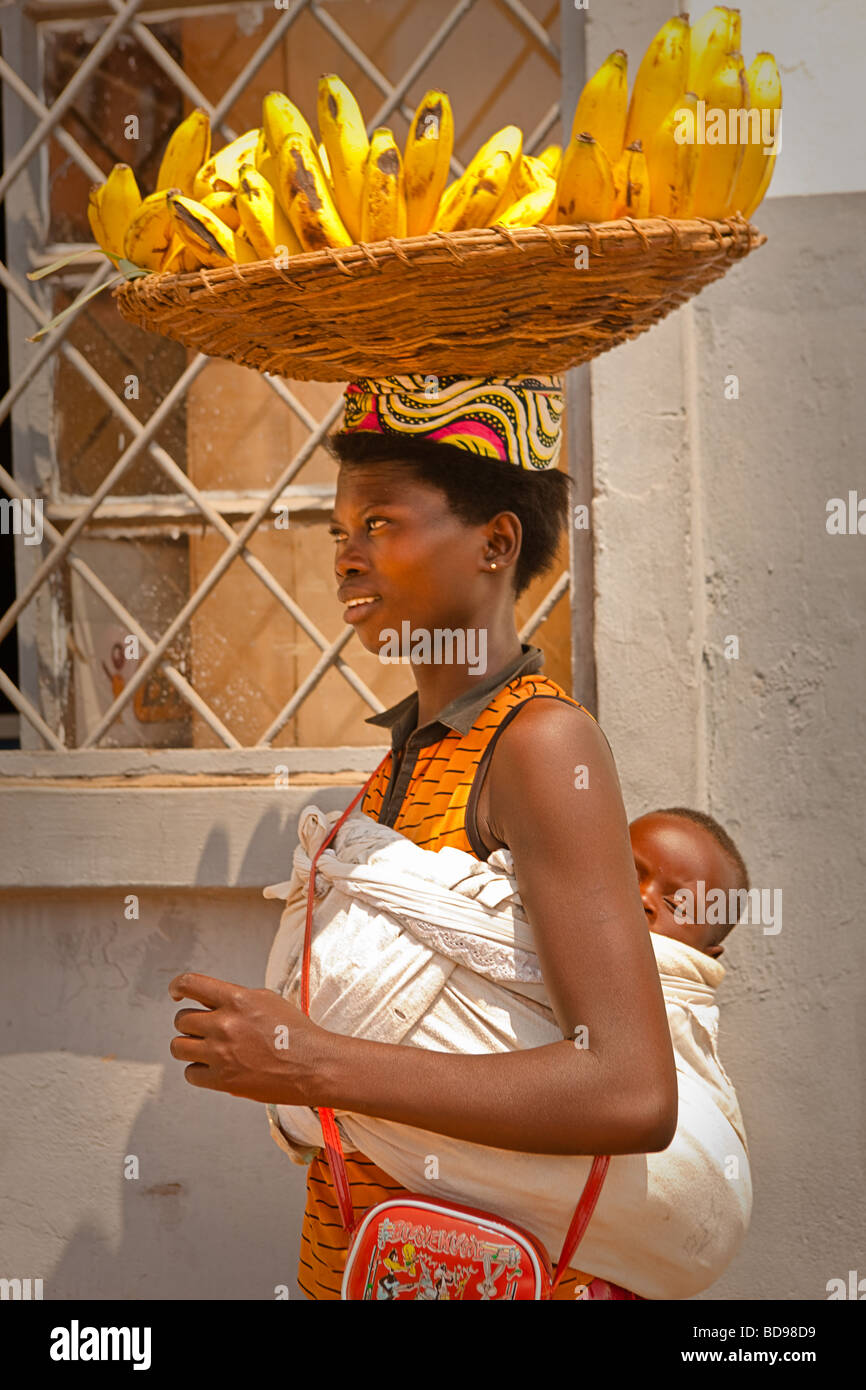Eine ruandische Frau Spaziergänge durch die Innenstadt von Kigali verkaufen Bananen mit einem Kind im Tragetuch auf dem Rücken Stockfoto