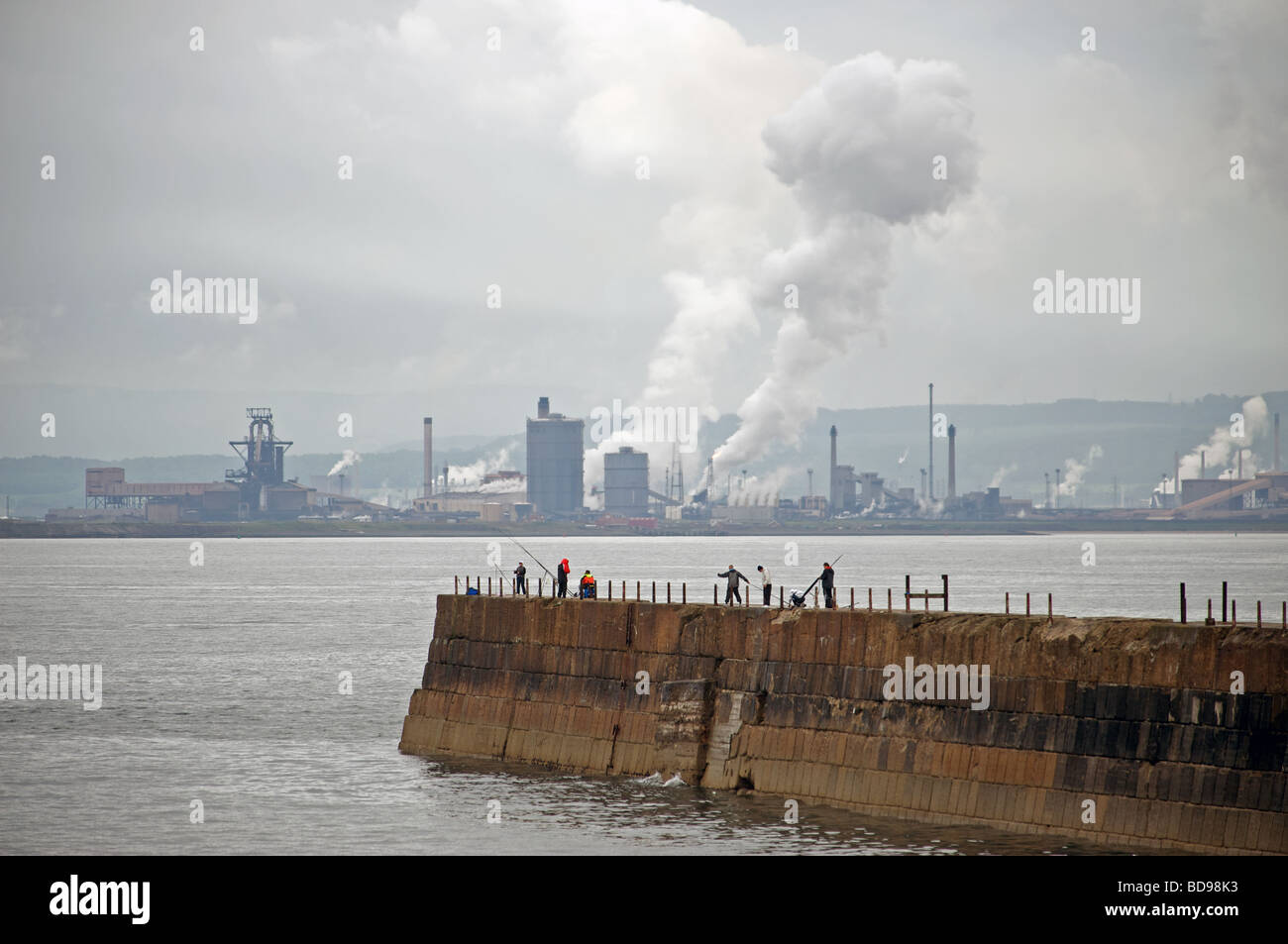 Angler, die von der Landzunge in Hartlepool mit Corus Stahlfabrik in Redcar im Hintergrund Stockfoto