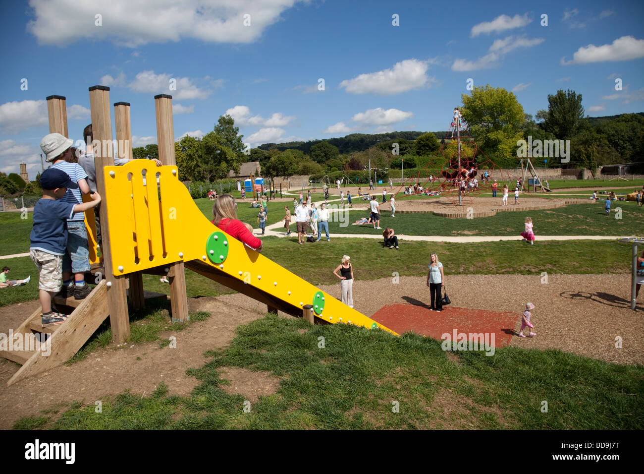 Kinder warten auf Folie am neuen Broadway Activity Park Wocestershire UK zu benutzen Stockfoto