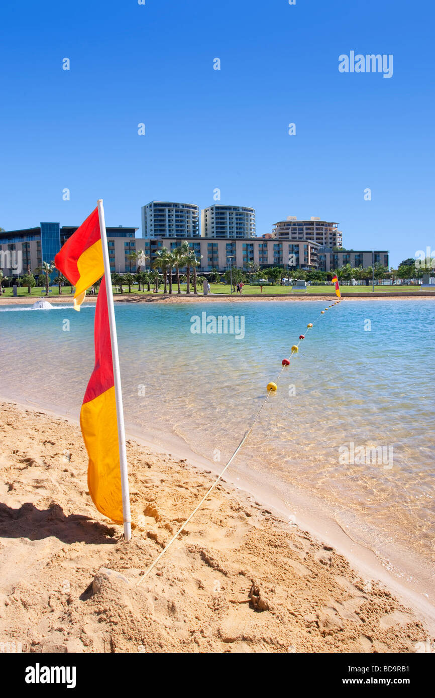 Ein Surf Lifesaving Flagge am Strand von Darwin Waterfront Recreation Lagoon. Ein Netz schützt die Lagune vor Quallen. Stockfoto
