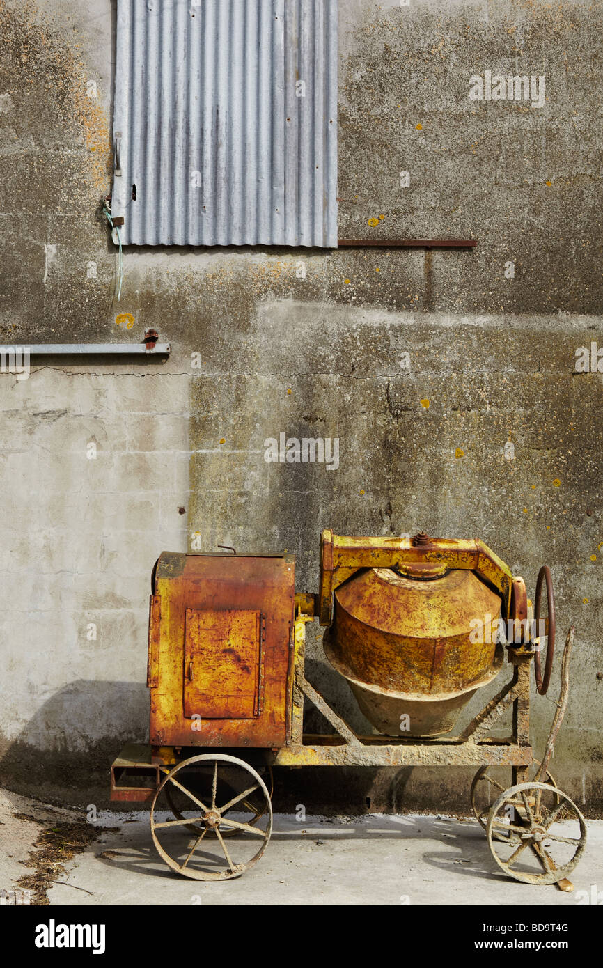 eine alte Betonmischer vor einer Betonwand Stockfoto