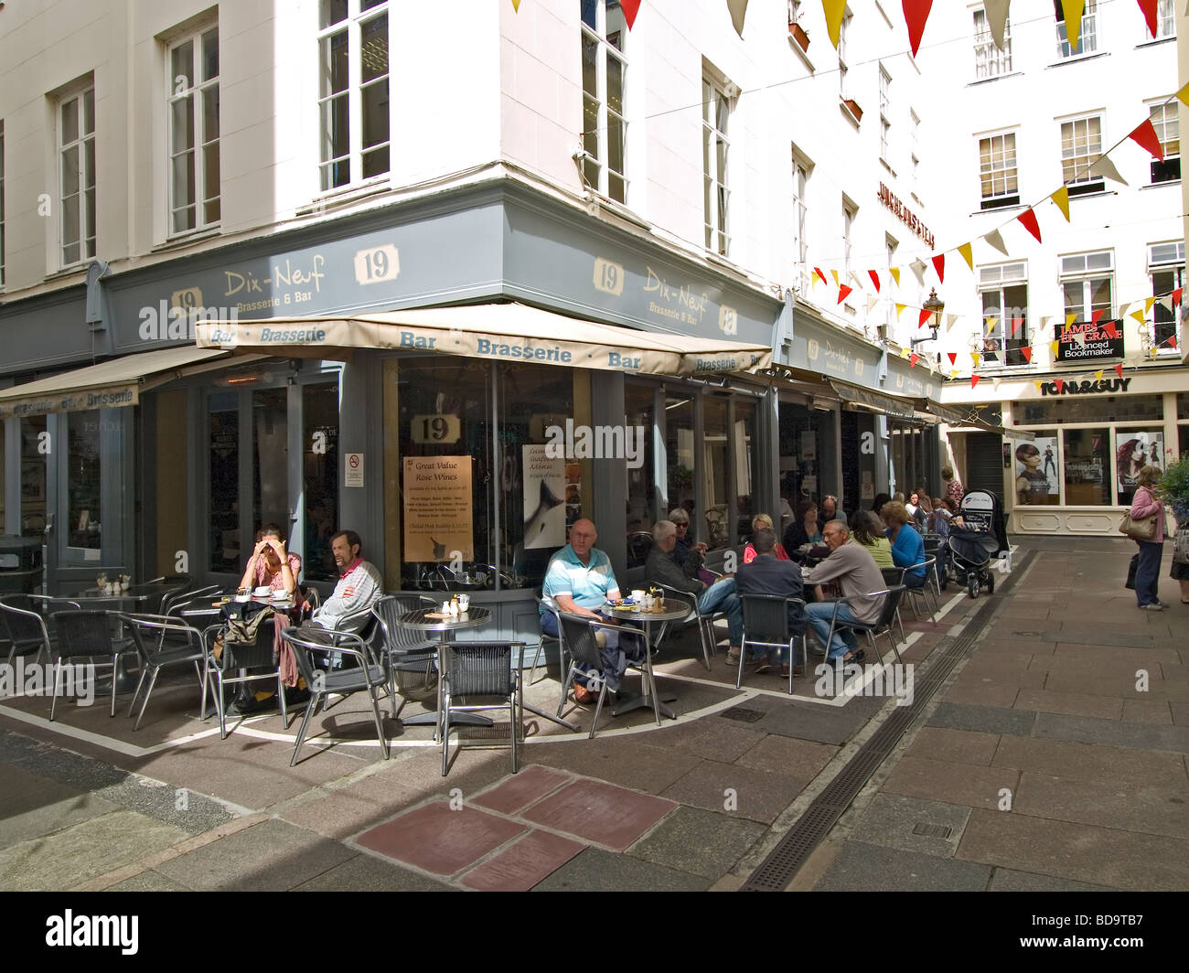 Kunden, die Entspannung in einem Straßencafé in der Spielhalle einer Fußgängerzone in St Peter Port Guernsey Stockfoto