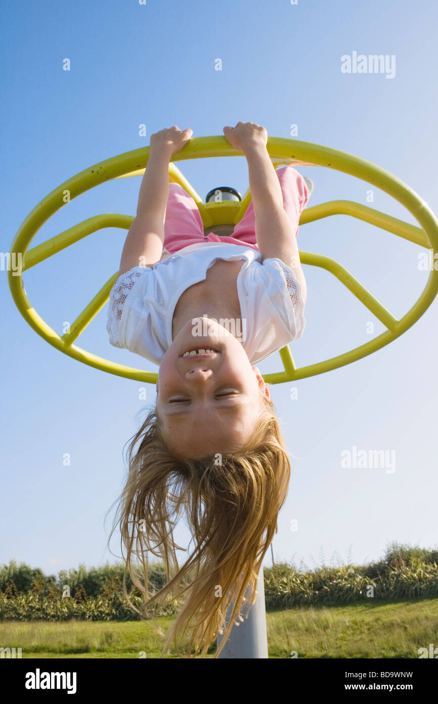Kleines Mädchen auf Spielplatz kopfüber hängend Stockfoto