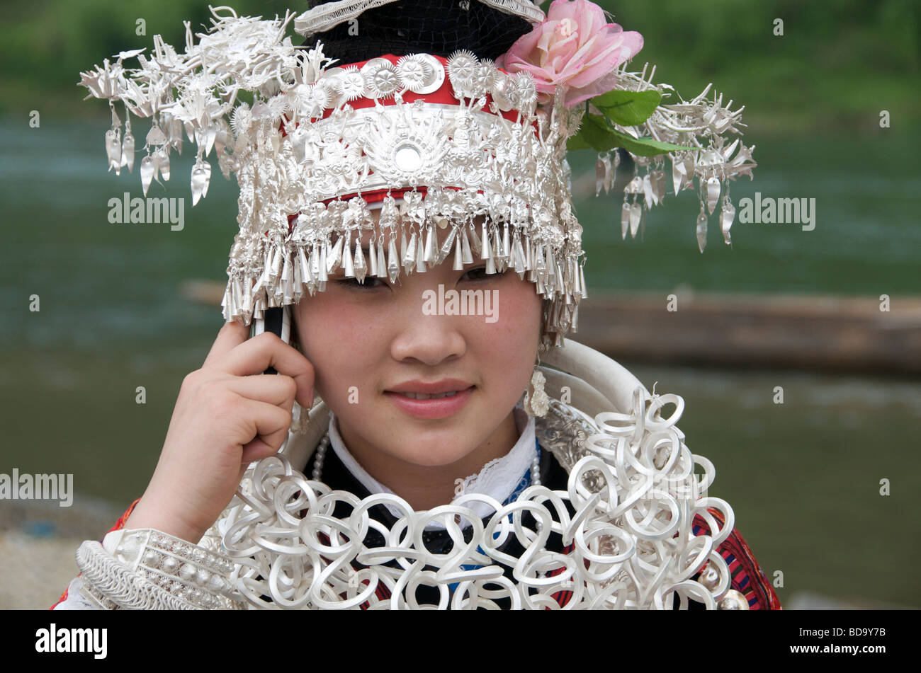 Miao Mädchen auf Handy und gekleidet in formalen Kostüm bei Drum Festival Shidong Guizhou Provinz China hautnah Stockfoto