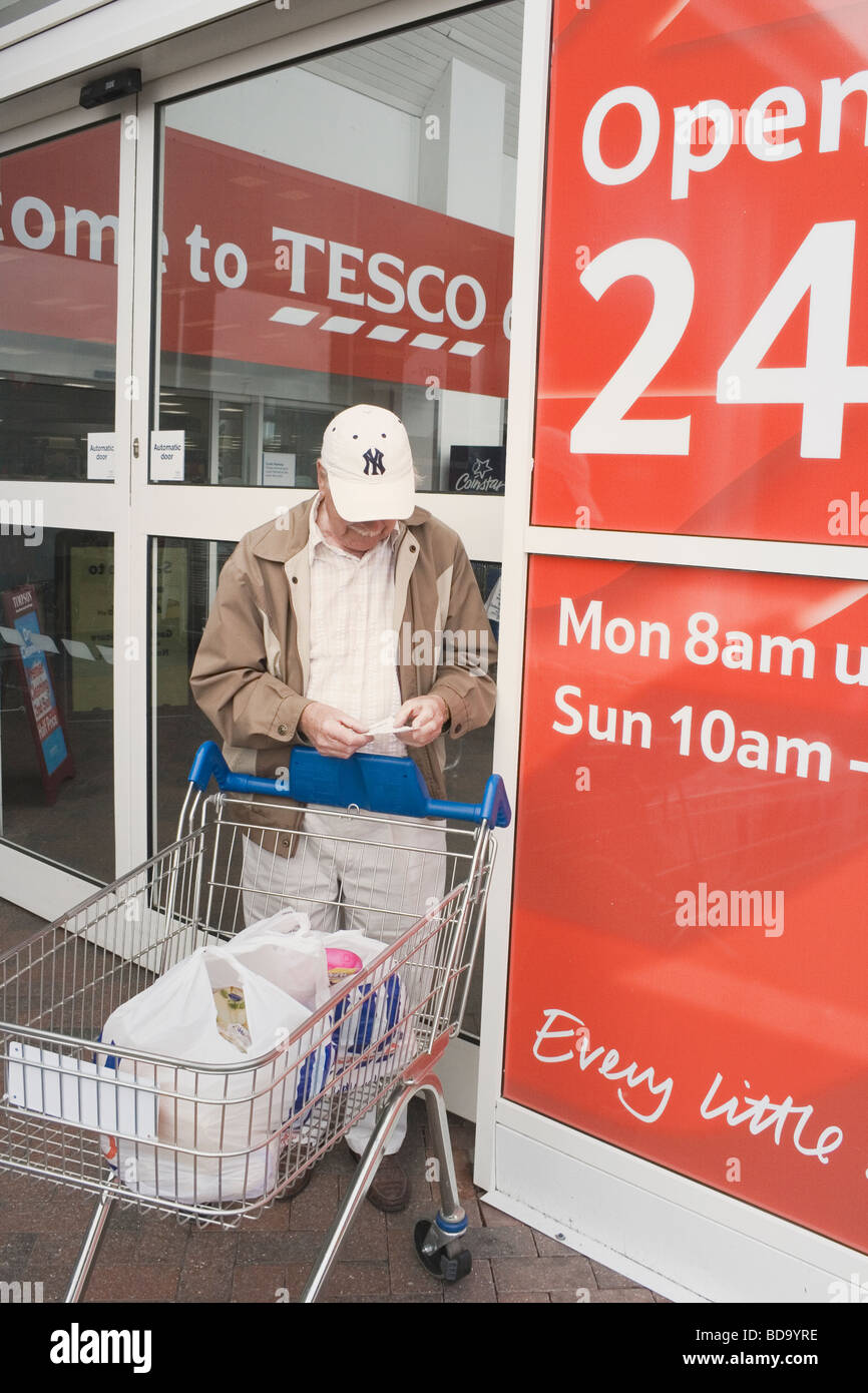 Alter Mann Überprüfung seiner Eingang außerhalb Tesco Supermarkt Blackpool Lancashire England Stockfoto