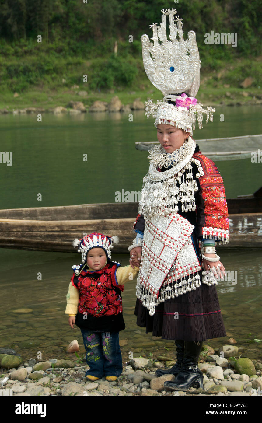 Mutter und Kind in Abendkleidung am Flussufer posiert für Fotos in der Provinz Guizhou Miao Drum Festival Shidong China Stockfoto