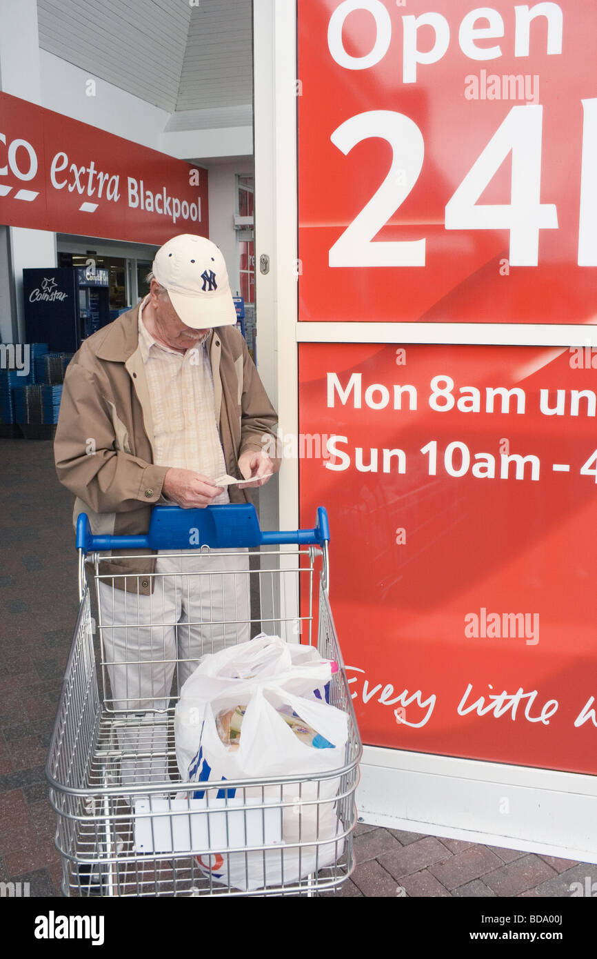 Alter Mann Überprüfung seiner Eingang außerhalb Tesco Supermarkt Blackpool Lancashire England Stockfoto