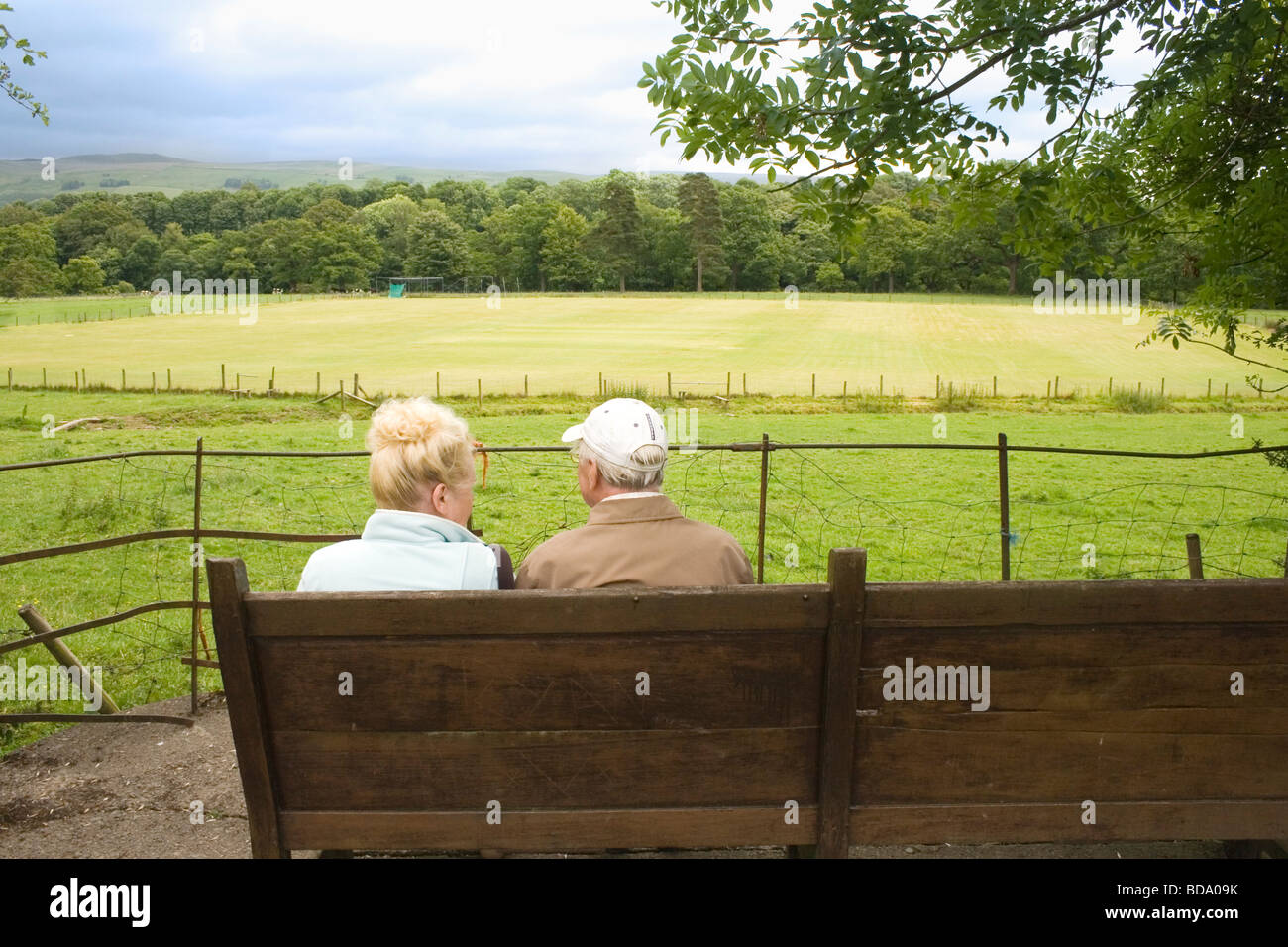 Älteres Ehepaar saß auf der Bank, plaudern und genießen die Aussicht Kirby Lonsdale Seenplatte Cumbria England Stockfoto