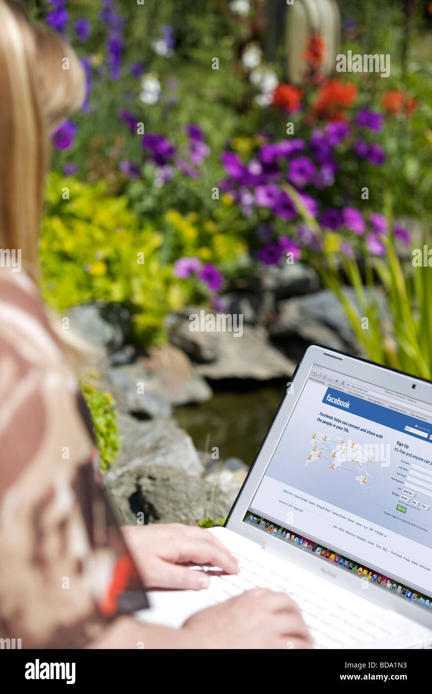 Frau mit Laptop zeigt soziale Netzwerk Facebook Splash-Bildschirm-Seite Stockfoto