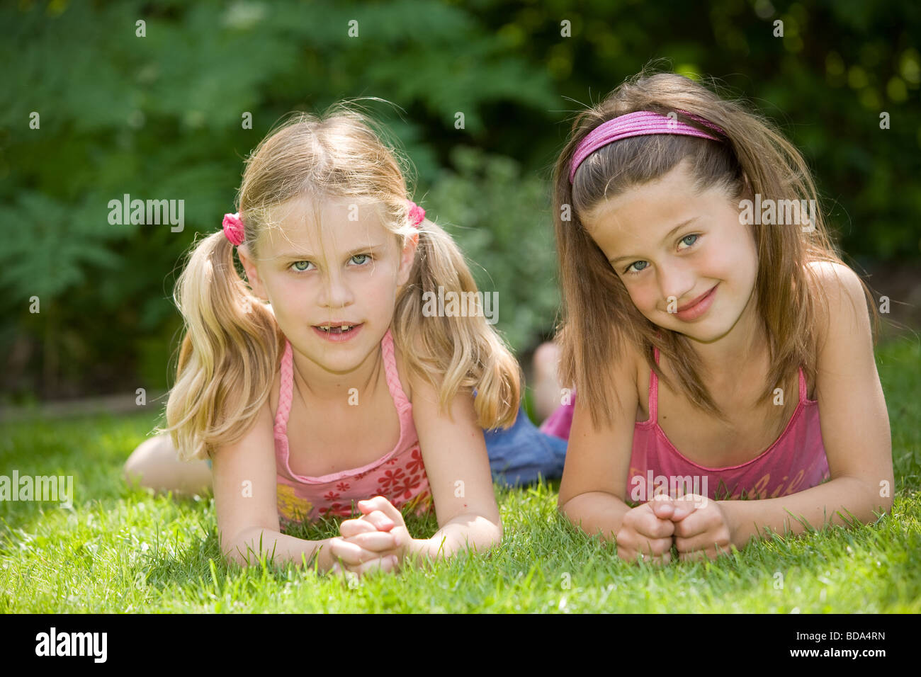 Zwei süße junge Mädchen liegen in der Wiese zusammen an einem Sommertag Stockfoto
