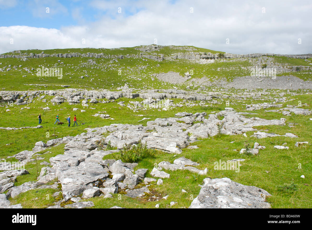 Vier Personen zu Fuß durch Kalksteinlandschaft in der Nähe von Malham, Yorkshire Dales National Park, North Yorkshire, England UK Stockfoto