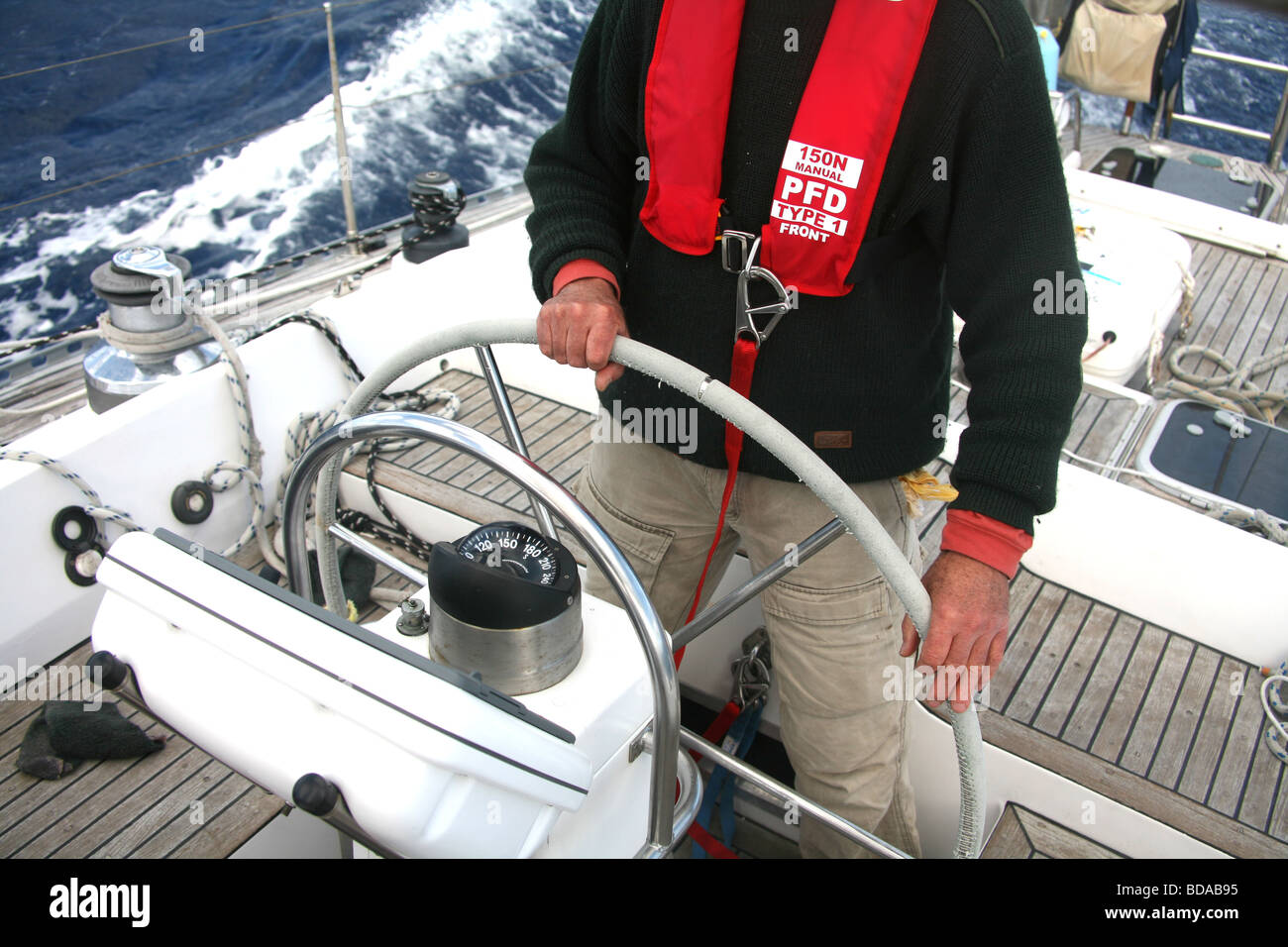 Der Steuermann auf einer modernen Yacht, die das Tragen einer Schwimmweste und Kabelbaum Stockfoto