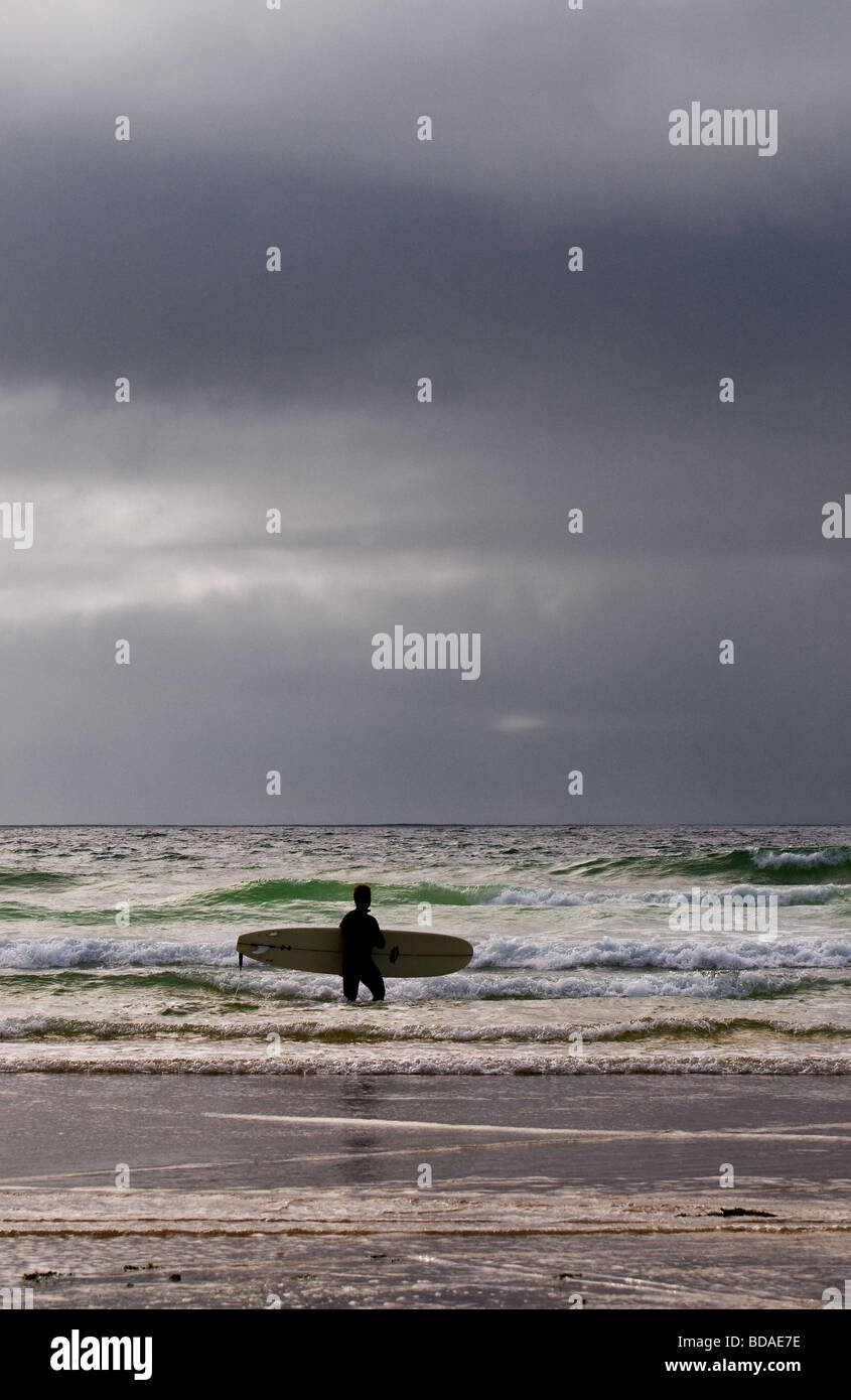 Ein Surfer, zu Fuß ins Meer in St Ives Bay in Cornwall. VEREINIGTES KÖNIGREICH. Stockfoto