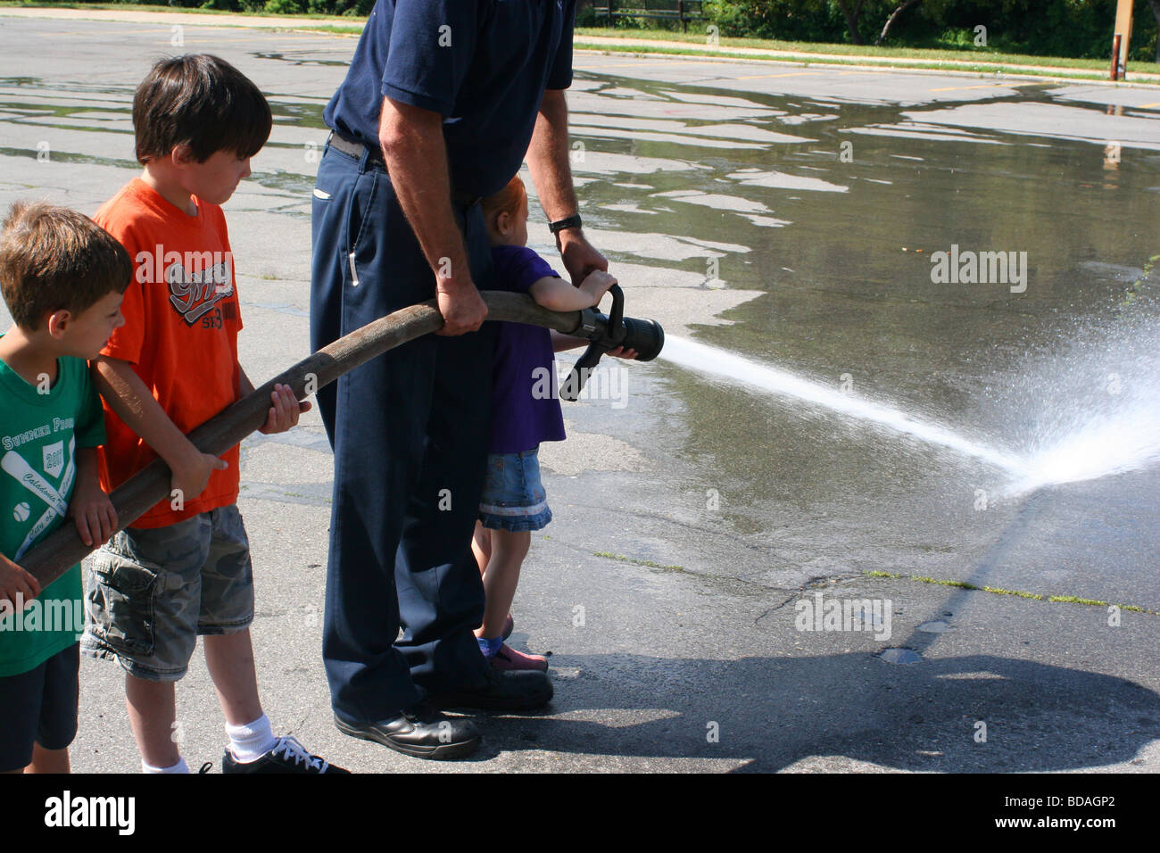 Kinder mit Feuer Schlauch mit Feuerwehrmann Owosso City Feuerwehr Tour Owosso MI USA Stockfoto