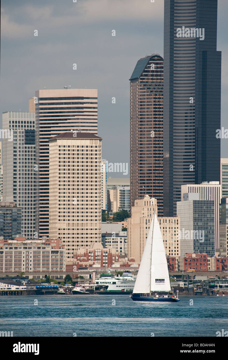 Ein Segelboot an der Elliott Bay cruises vorbei Coleman Dock und die Skyline der Innenstadt von Seattle, Washington in den Puget Sound. Stockfoto