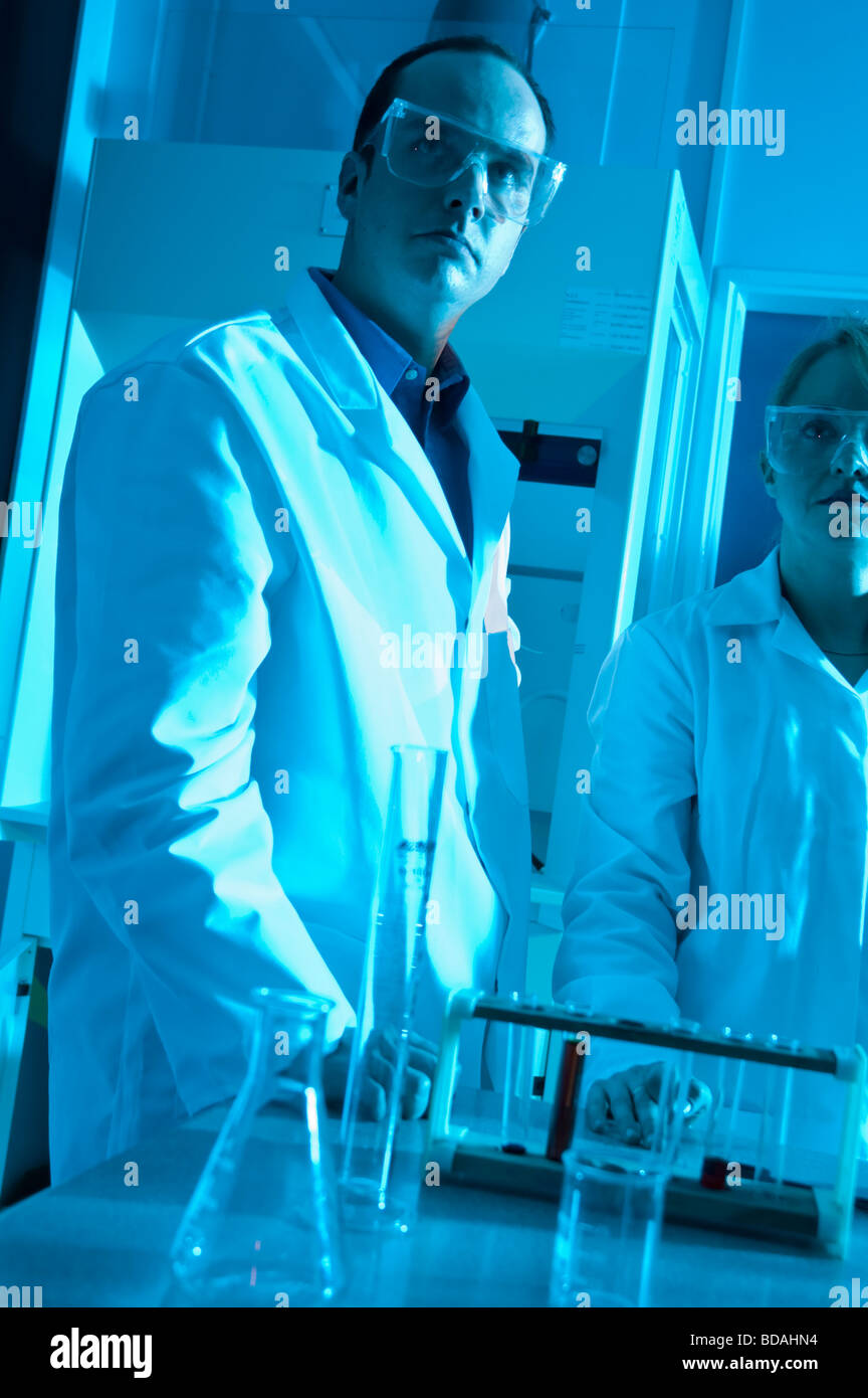 Frau und Mann im Laborkittel mit Laborgeräten blaues Licht Stockfoto