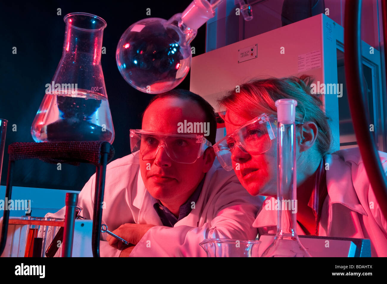 Frau und Mann im Laborkittel mit Lab Ausrüstung rotes und blaues Licht Stockfoto