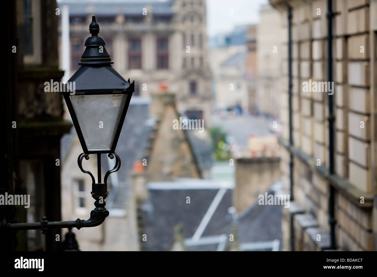 Eine alte Lampe mit Gas befeuerten steht stolz im setzt sich für enge, Edinburgh, mit Princes Street im tiefen Hintergrund sichtbar. Stockfoto