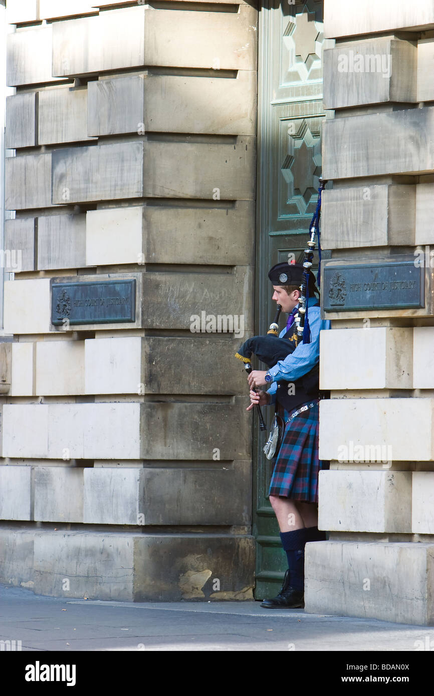 Eine Piper Unterstände aus dem Wind in der Tür des High Court in Edinburghs Royal Mile. Stockfoto
