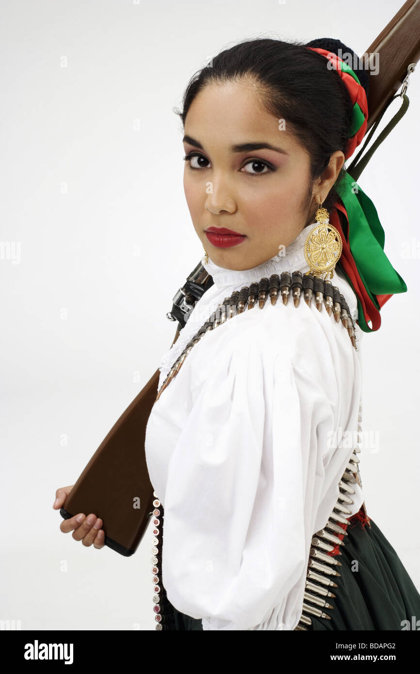 Porträt einer jungen Frau in typischen mexikanischen Tracht und hält eine Pistole Stockfoto