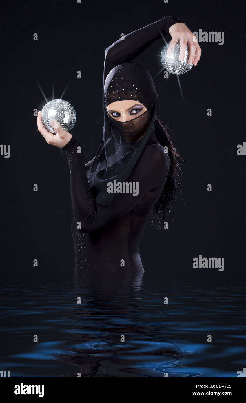 Partei-Tänzerin in Ninja-Kleid mit Disco-Kugeln Stockfoto