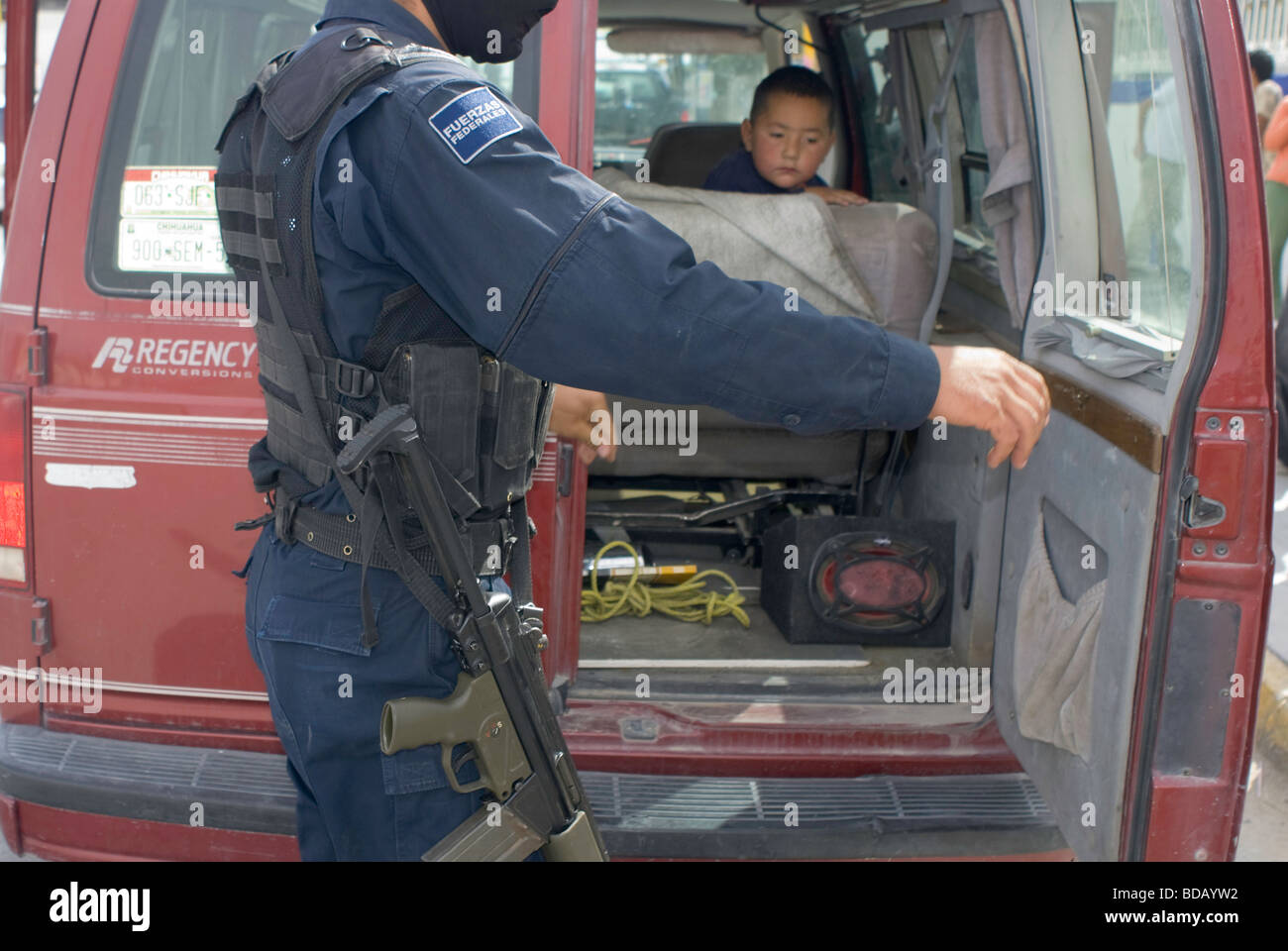Wie ein kleiner Junge schaut auf zwingt Bundespolizei Check Autos für Waffen und Drogen an einem Kontrollpunkt auf einer Straße in Ciudad Juarez Stockfoto