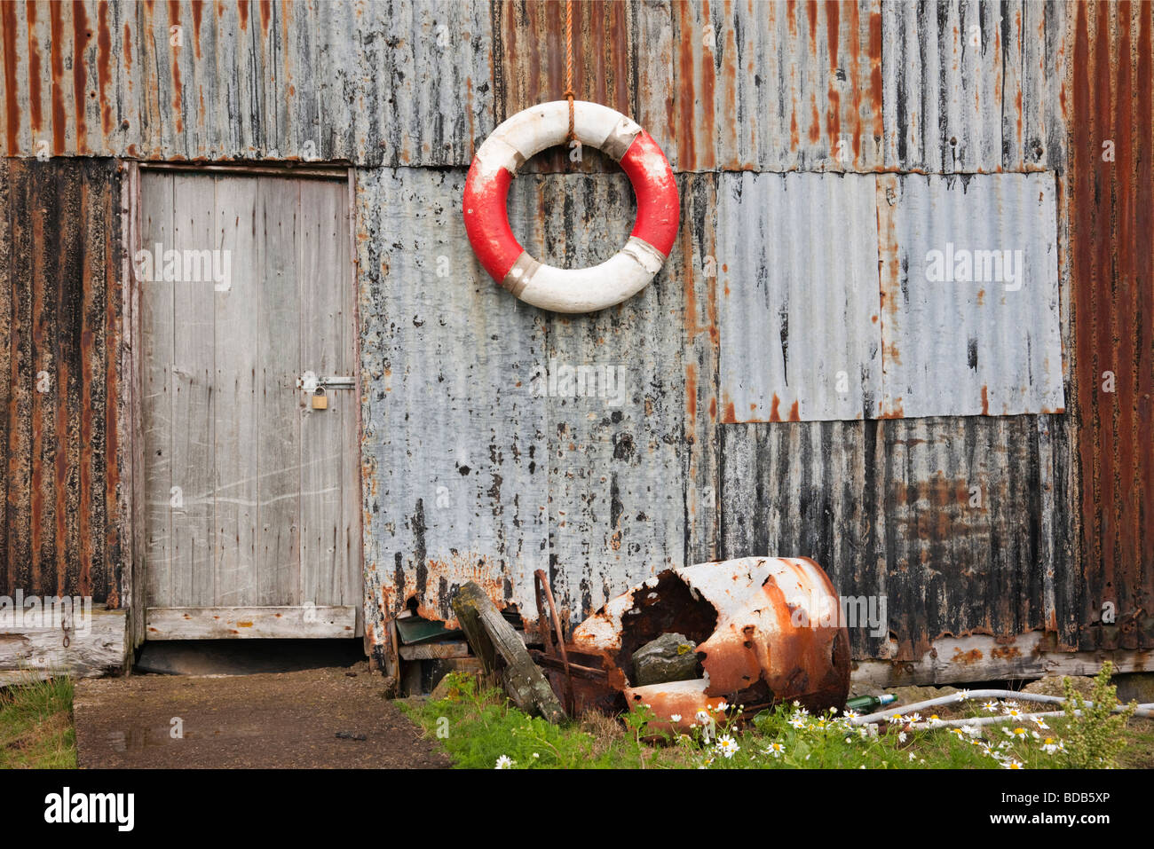 Großbritannien UK alte Rettungsring Ring hängen auf einem gewellten rostiges Eisenmetall Schuppen Wand Stockfoto