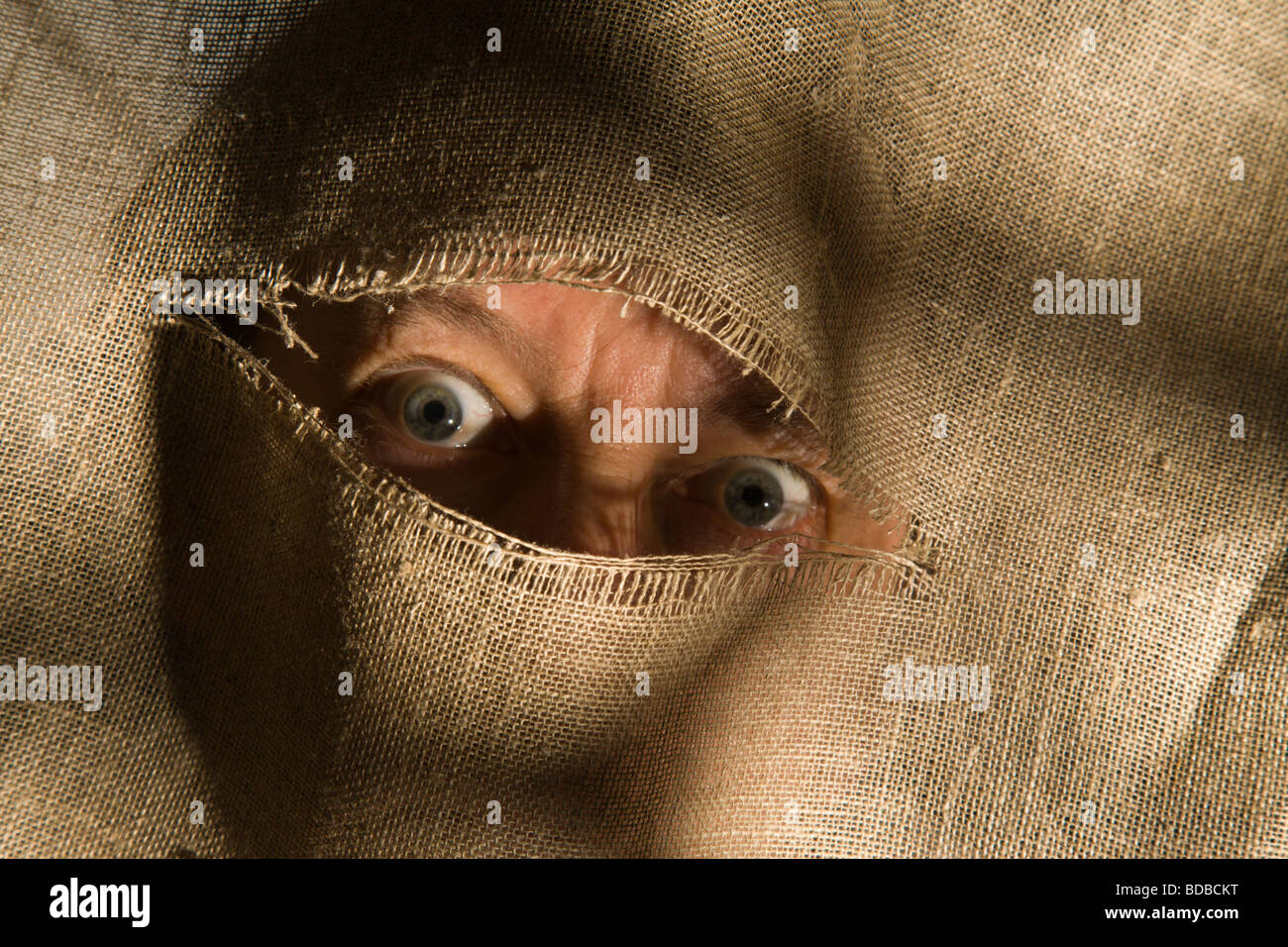Augen starren drohend durch einen Riss im Stoff Stockfotografie - Alamy