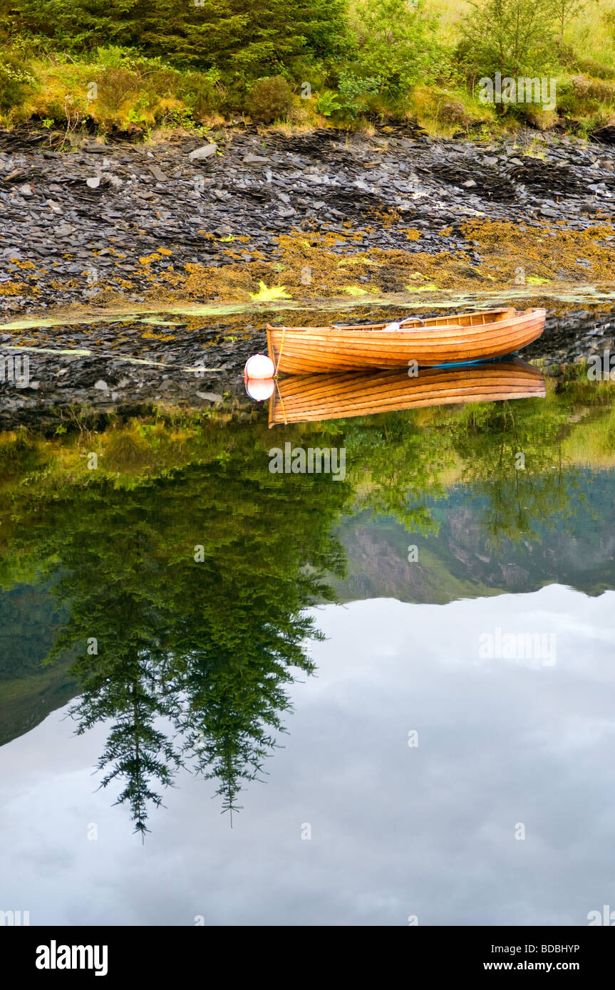 Ruderboot und ihre Reflexion vor Anker in einer kleinen Bucht am Loch Leven, Schottland. Stockfoto
