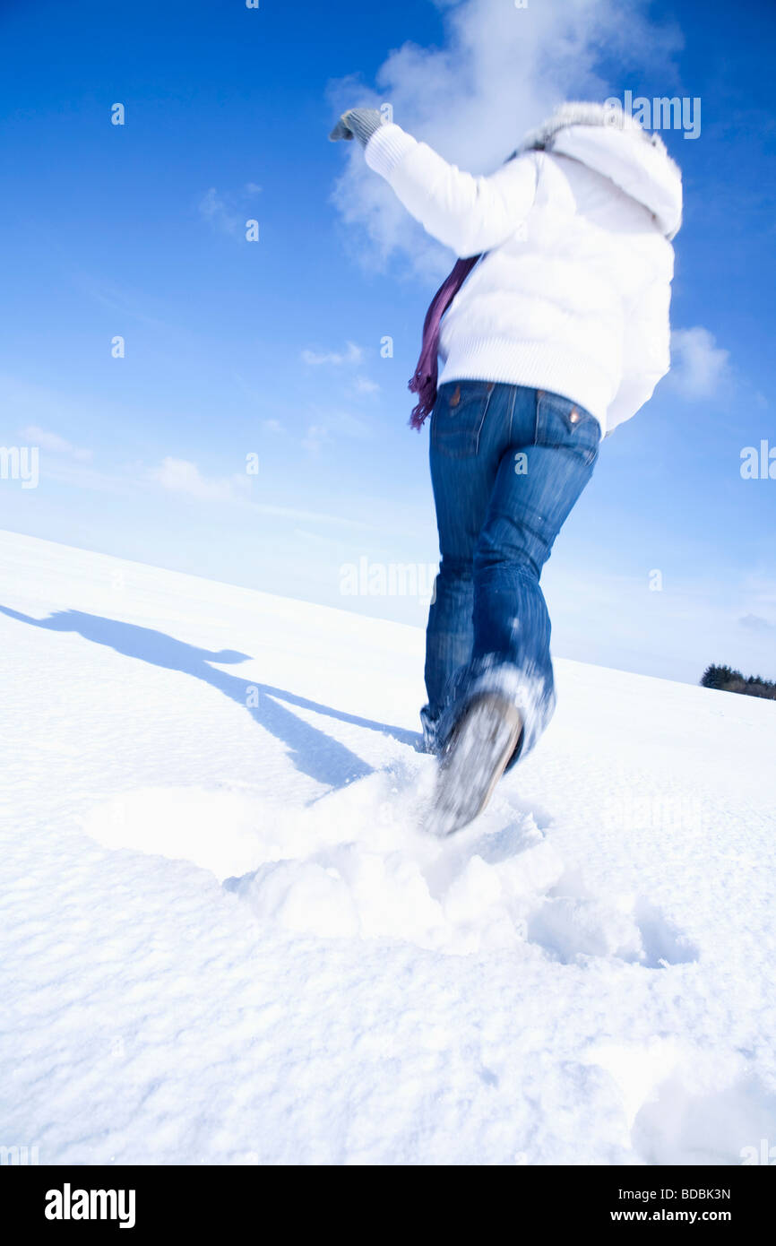 Heckansicht des jungen Frau läuft durch Schnee Stockfoto