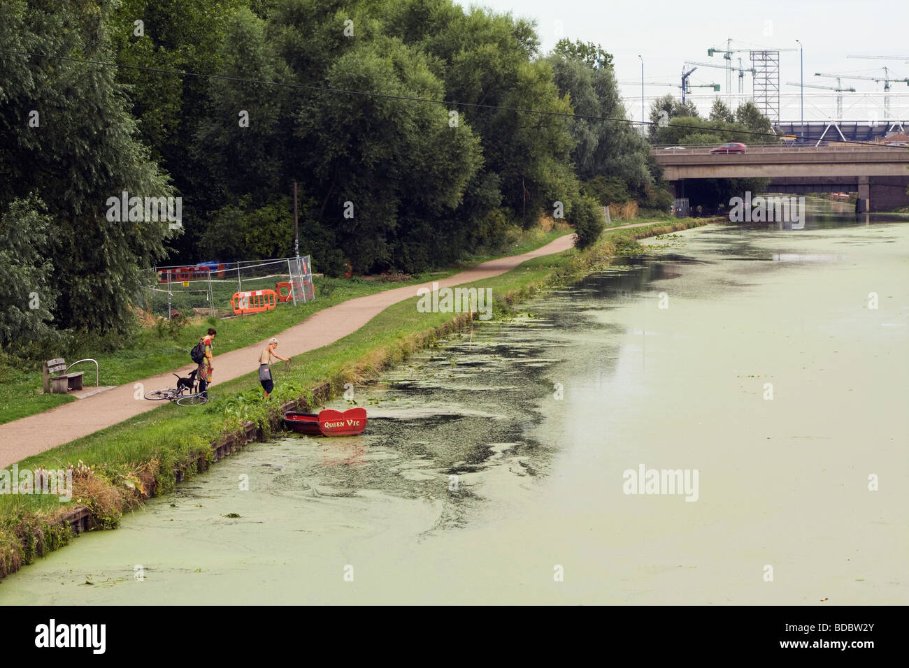 Fluss Lee bedeckt Ente Unkraut, eine Frau, ein Hund und ein Boot. Stockfoto