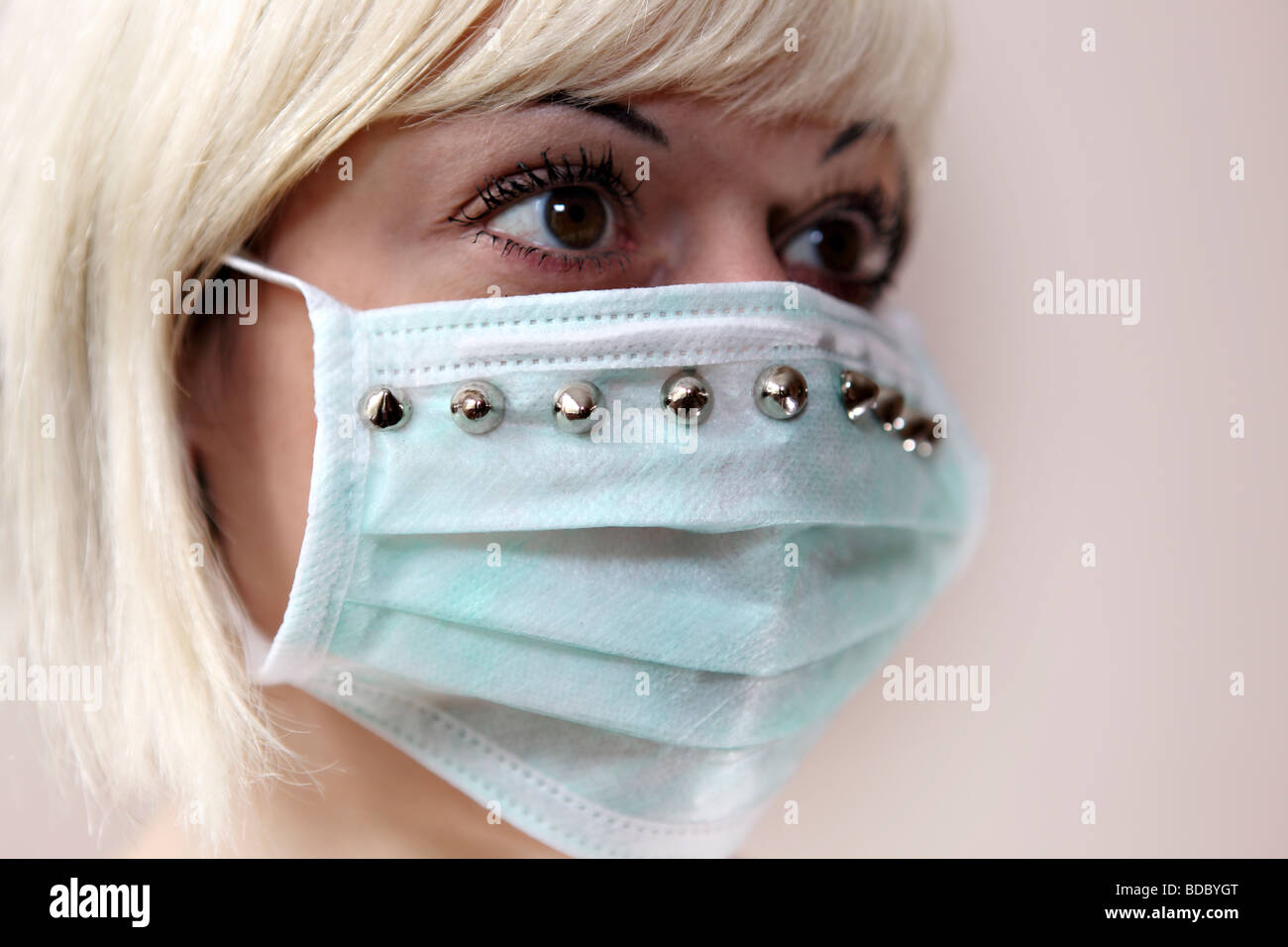 Ein blondes Mädchen trägt eine maßgeschneiderte chirurgische Gesichtsmaske. Stockfoto
