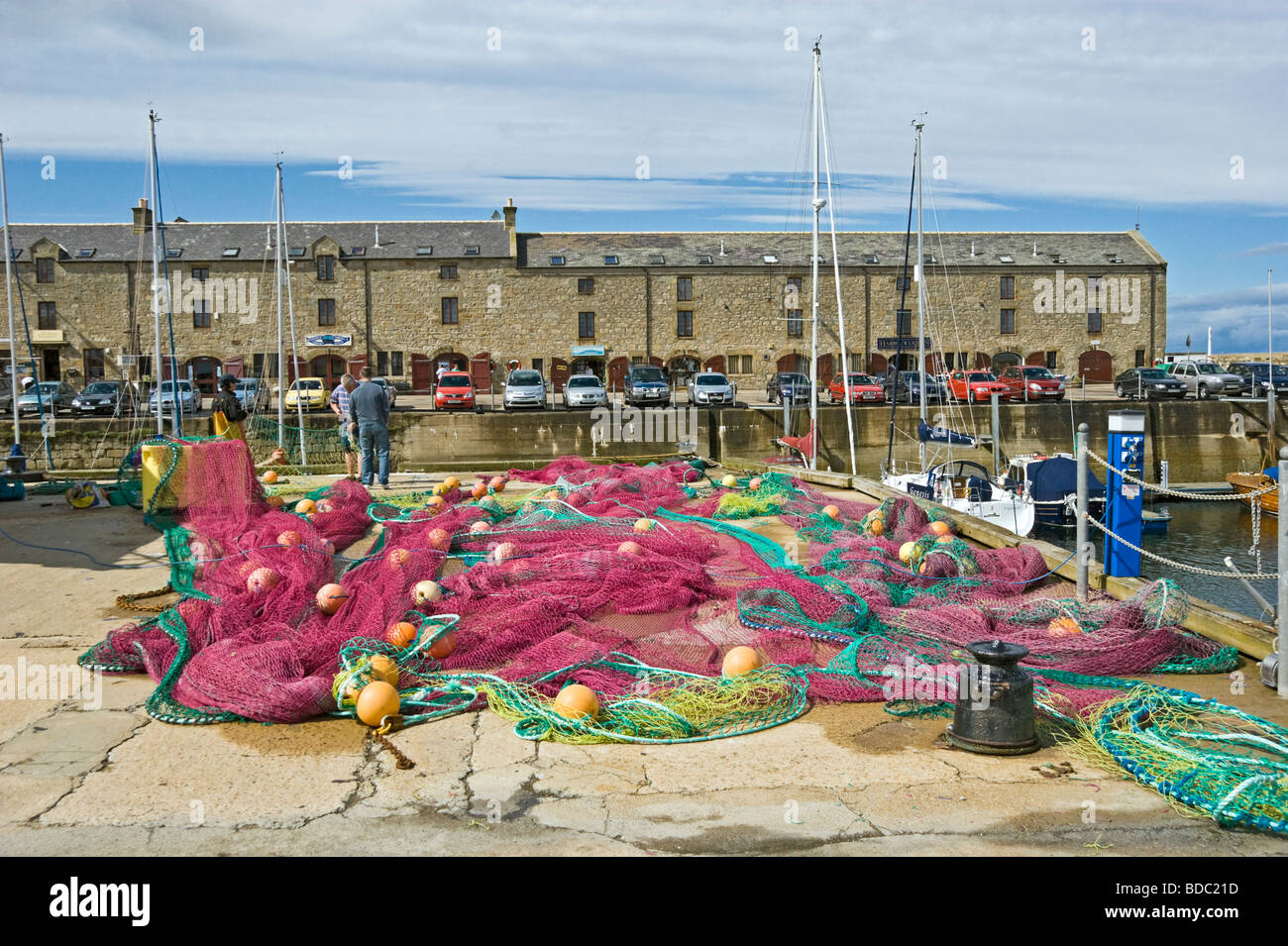 Ausbessern von Fischernetzen vor Geschäften und Restaurant in restauriertes Gebäude Lossiemouth Hafen Moray Schottland Stockfoto