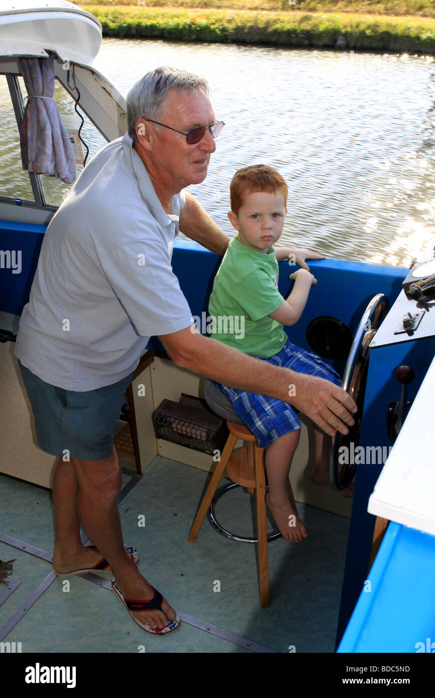 ein Großvater lehrt seinem Enkel, wie man ein Boot fahren Stockfoto