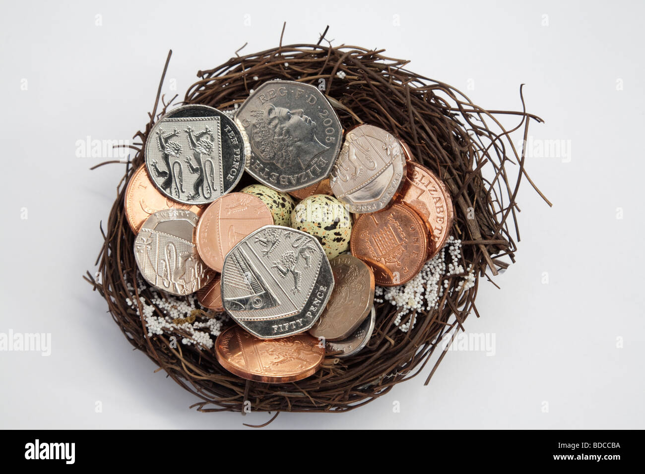 UK-Münzen in verschiedenen Stückelungen auf ein künstliches Nest mit Eiern von oben. England-Großbritannien Stockfoto