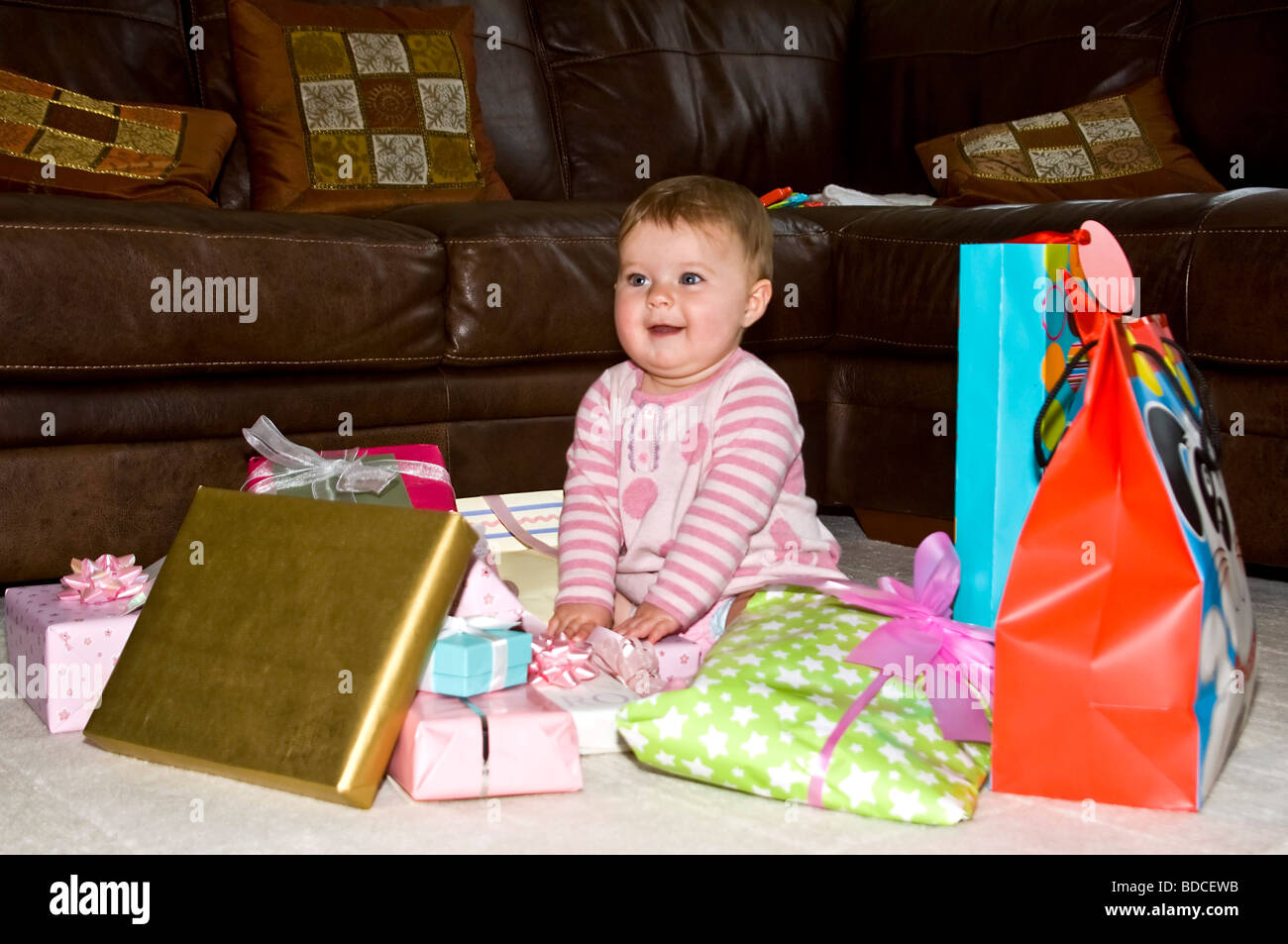 Horizontale Porträt von einem wunderschönen Babymädchen umgeben von vielen ihr ungeöffnete Geschenke. Stockfoto
