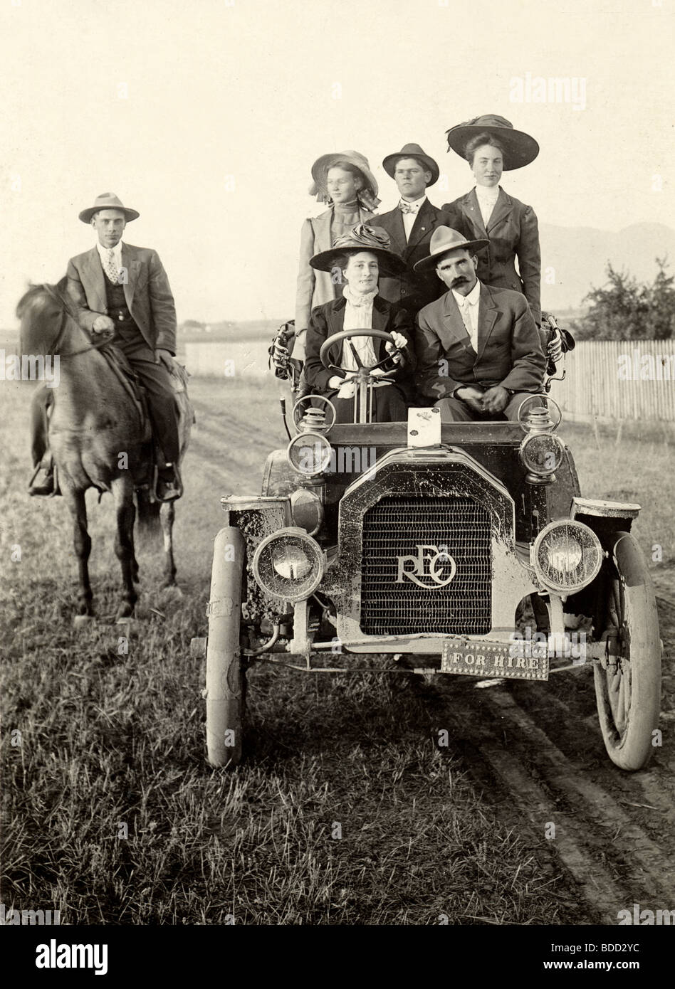 Fünf Menschen im antiken Reo Auto & Mann auf dem Rücken der Pferde Stockfoto