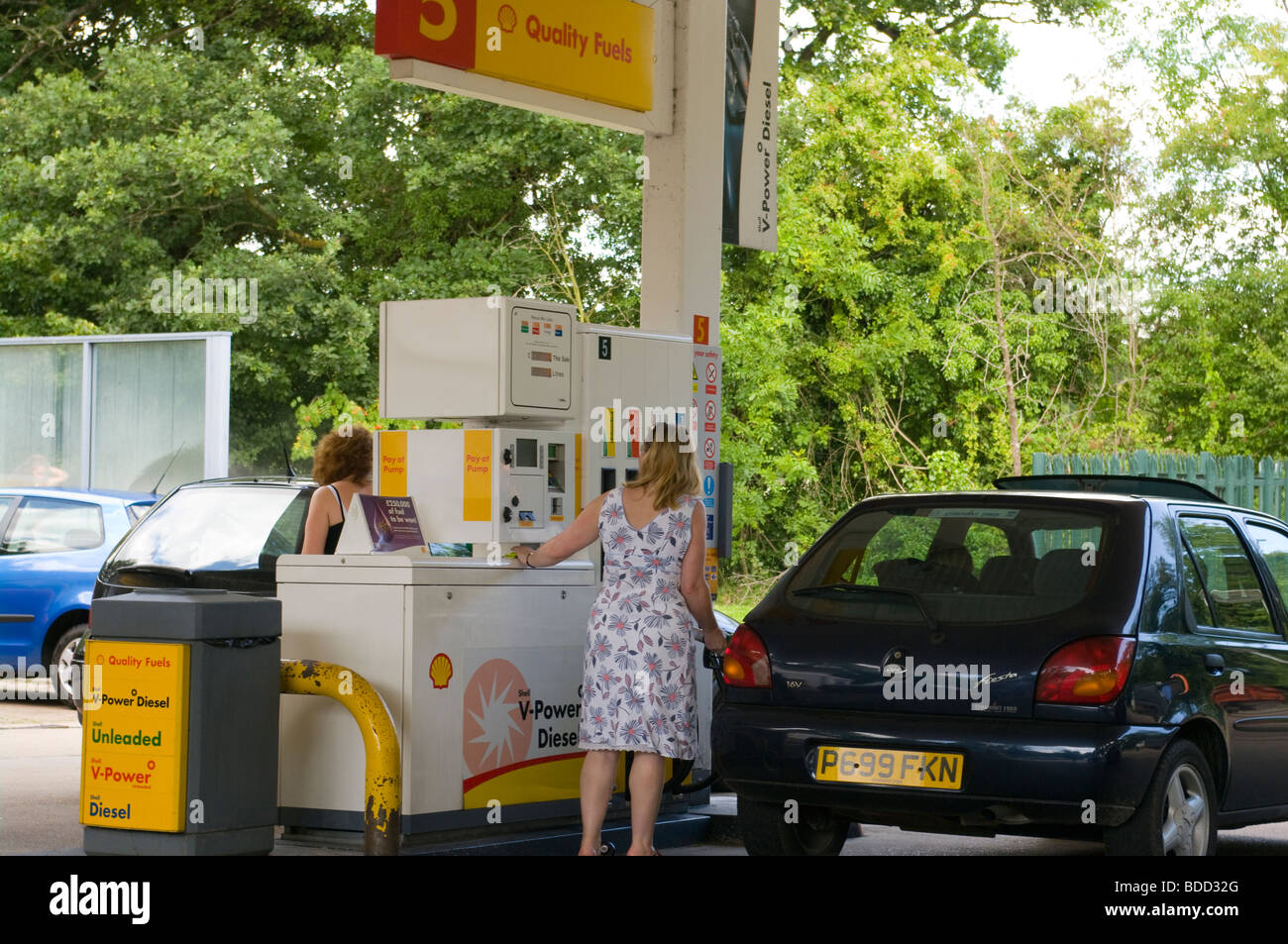 Zwei Frauen füllt ihre Autos mit Benzin auf eine Shell Station Vorplatz Stockfoto