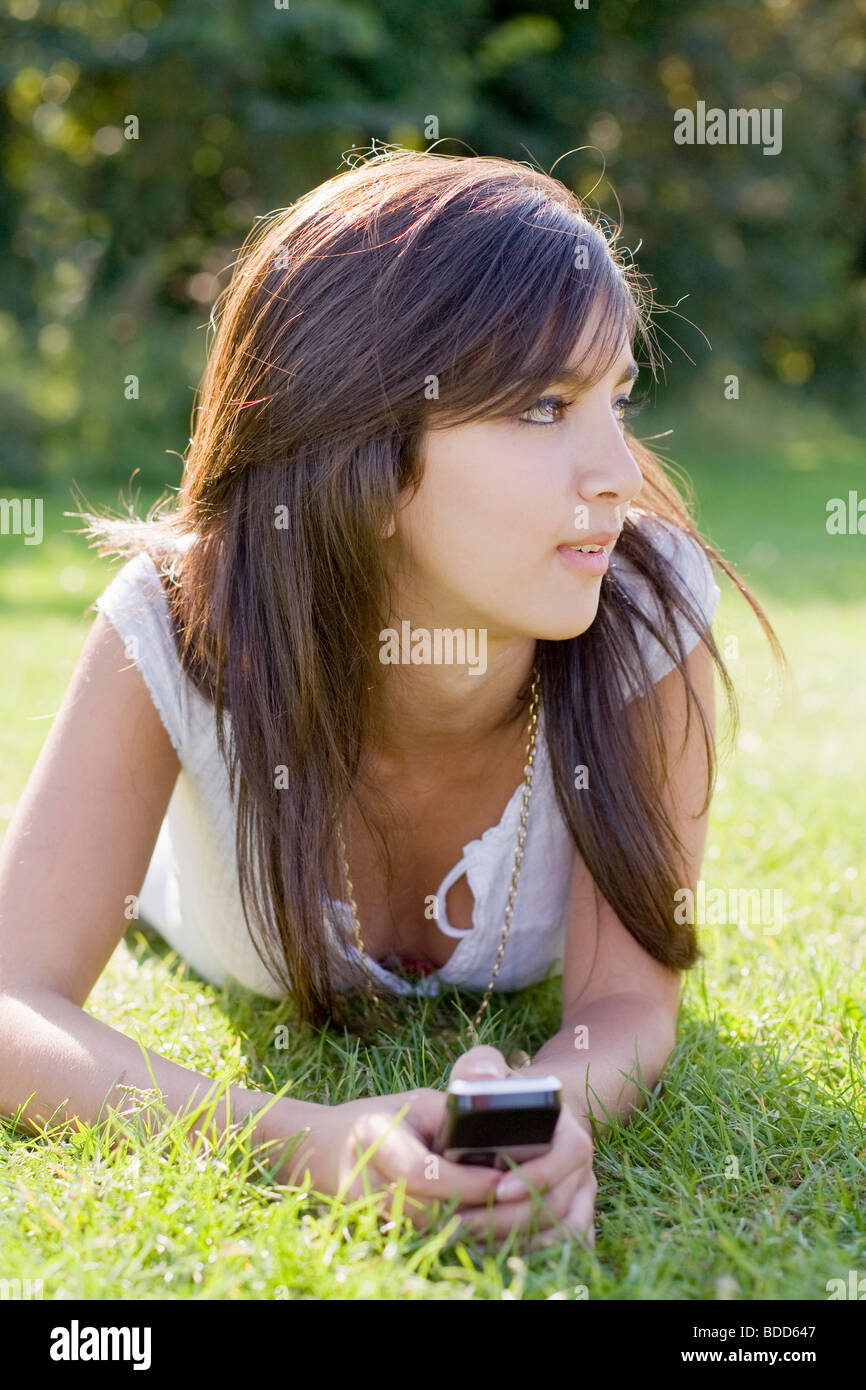 Teenager-Mädchen liegen auf dem Rasen mit Handy Stockfoto