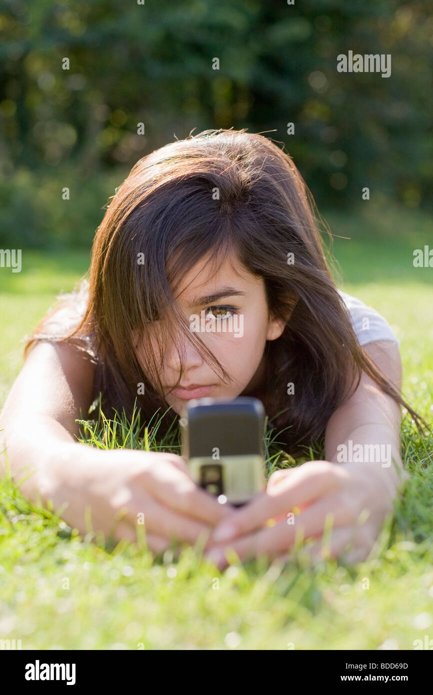 Teenager-Mädchen liegen auf dem Rasen mit Handy Stockfoto