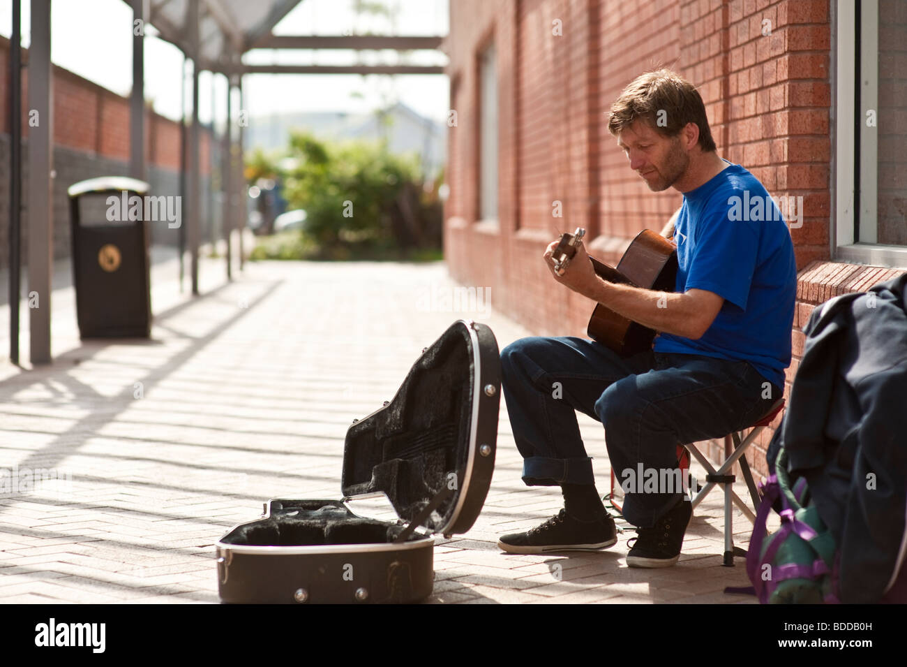 Mann als Straßenmusikant, Gitarre spielen, auf die leere Straße, UK Stockfoto