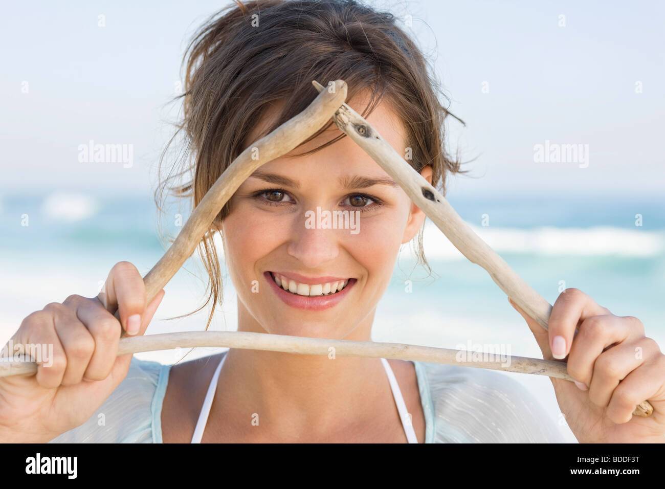 Frau macht Dreiecksform mit Stöcken Stockfoto